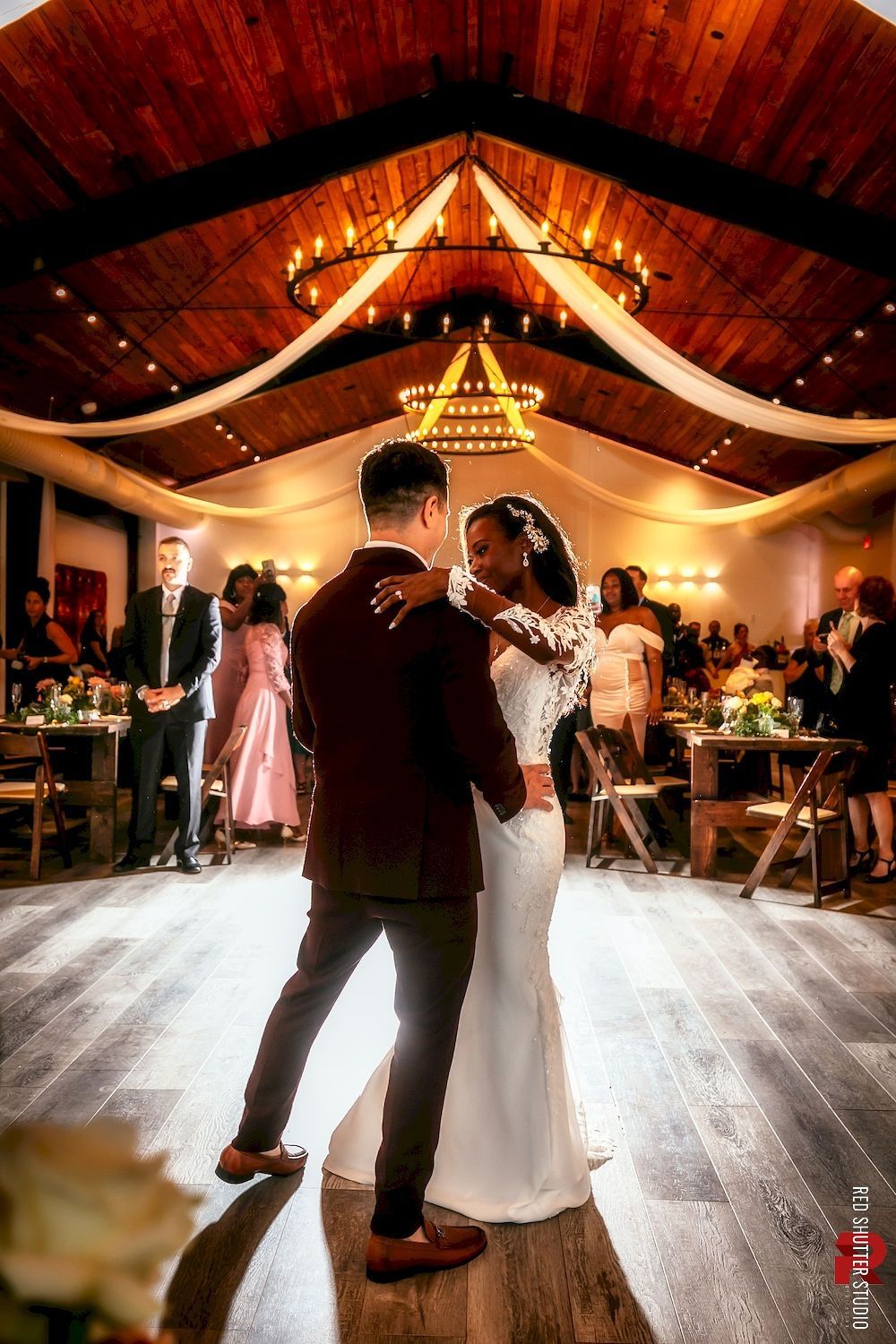 Couple slow dancing at a warmly lit wedding reception under draped ceiling decor