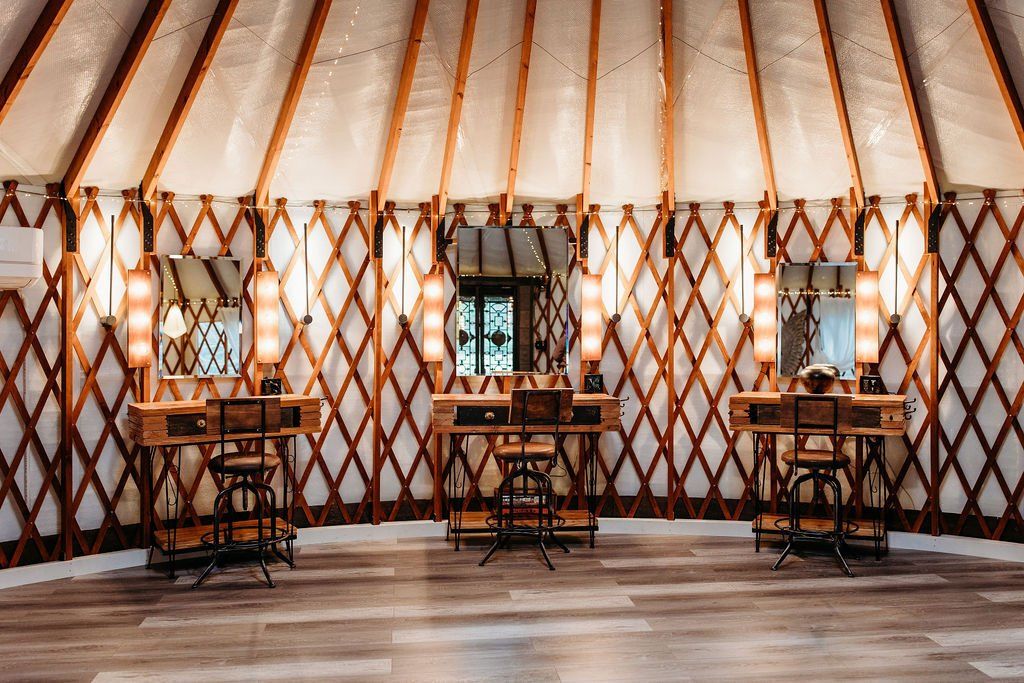 Spacious yurt interior with wooden tables, patterned wall lattice, and warm hanging lights