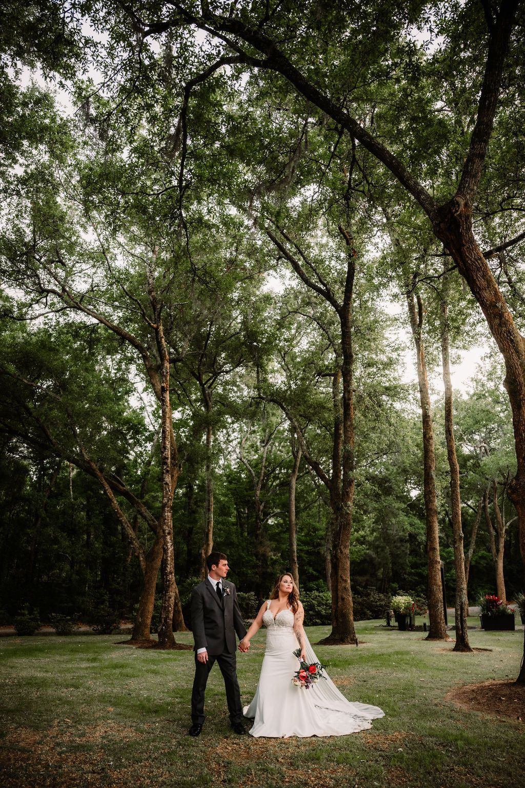 Bride and groom posing in white and black formalwear in a wooded park setting