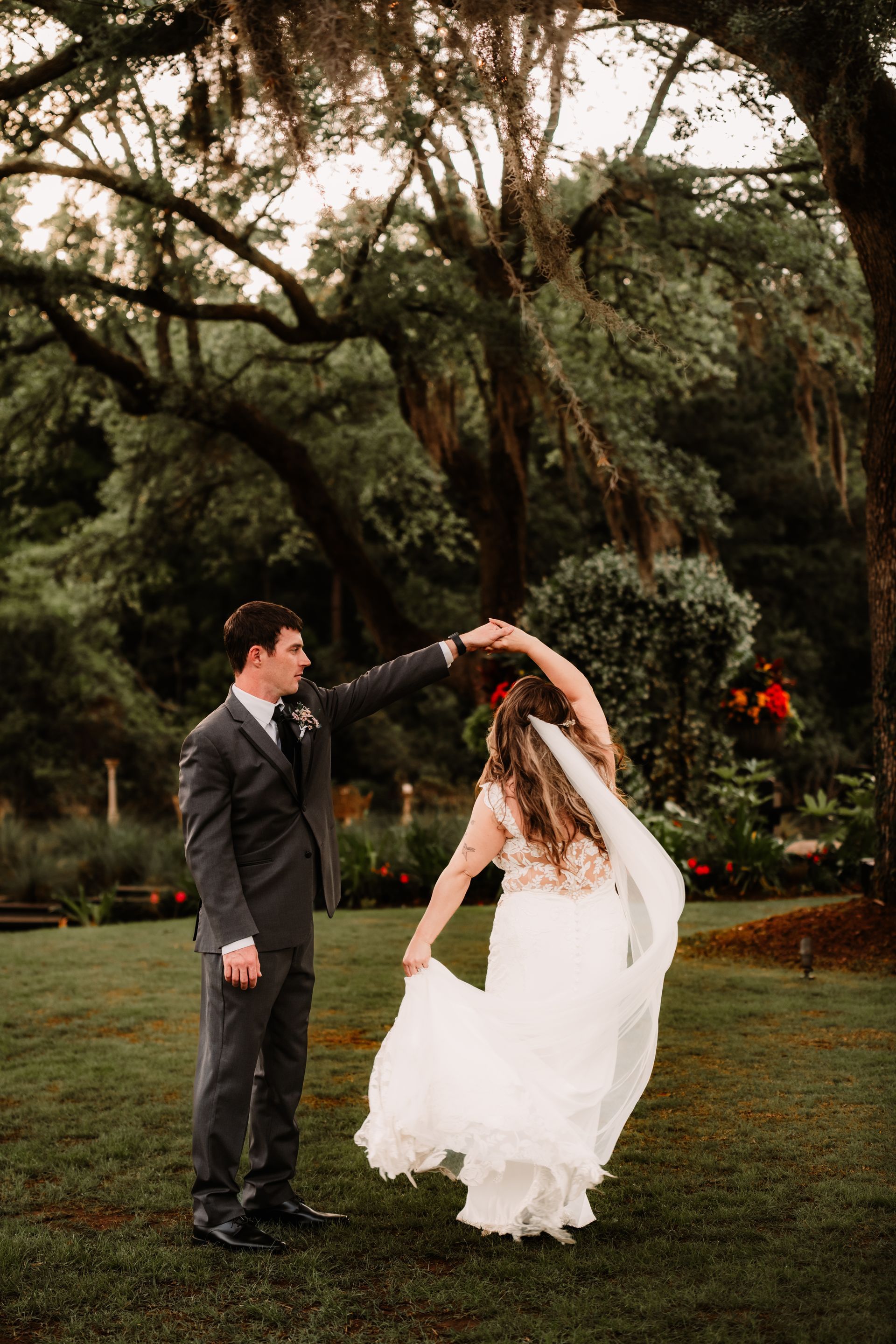 Bride and groom dance in a garden under large trees