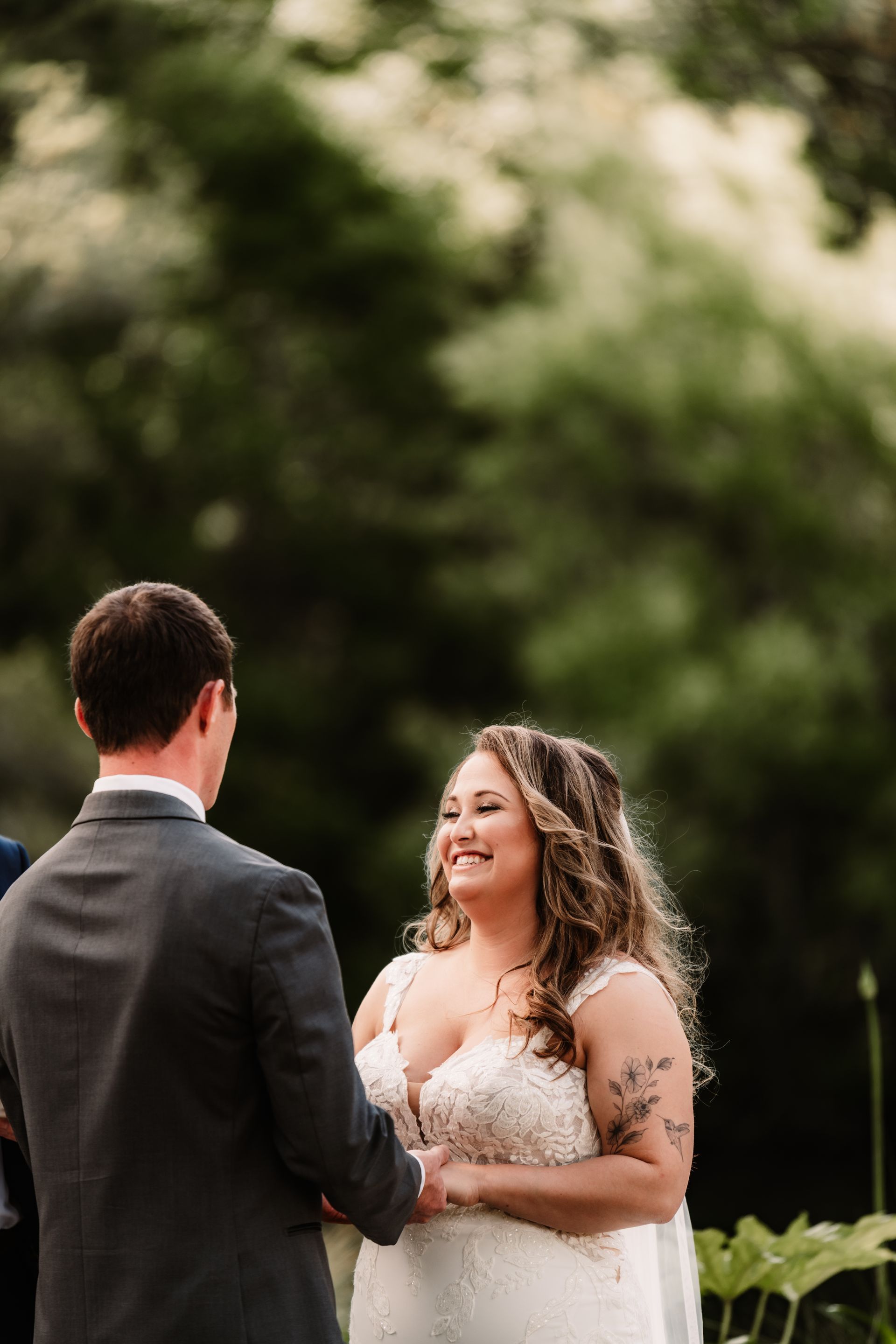 Bride and groom holding hands outdoors, smiling during a wedding ceremony