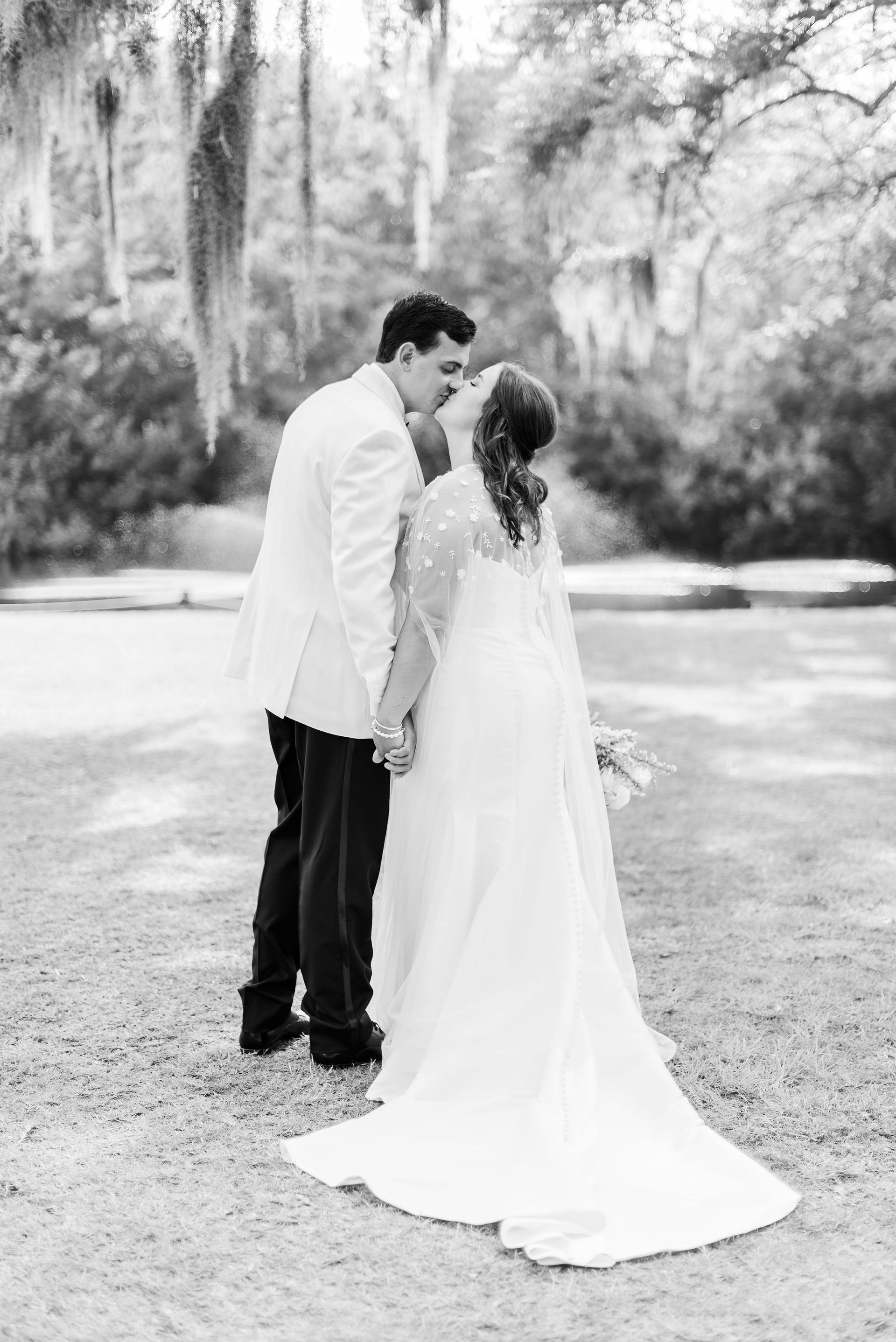 Bride and groom kissing outdoors in a black-and-white wedding portrait