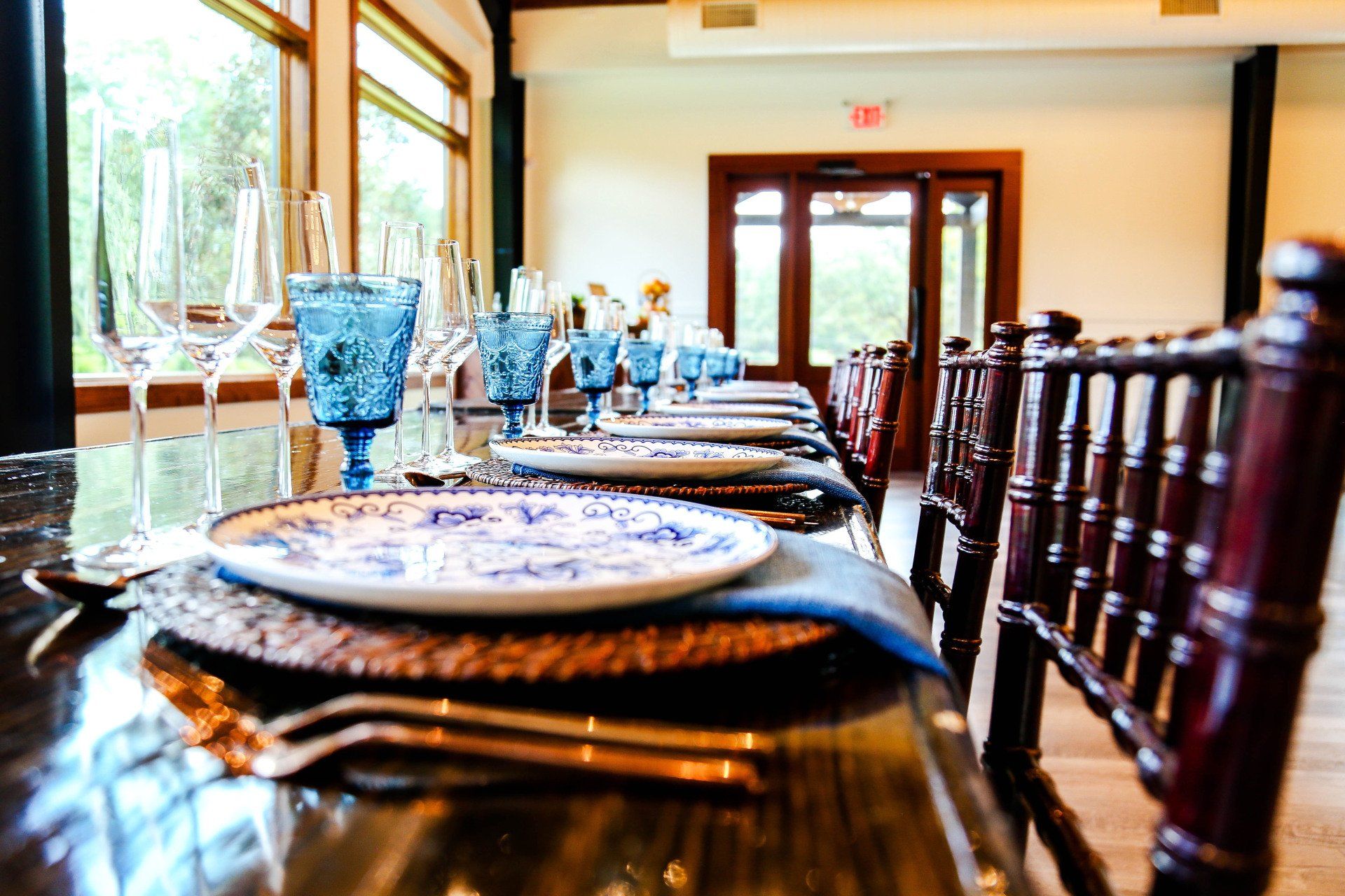 Set dining table in a bright restaurant with blue glassware and white plates by large windows