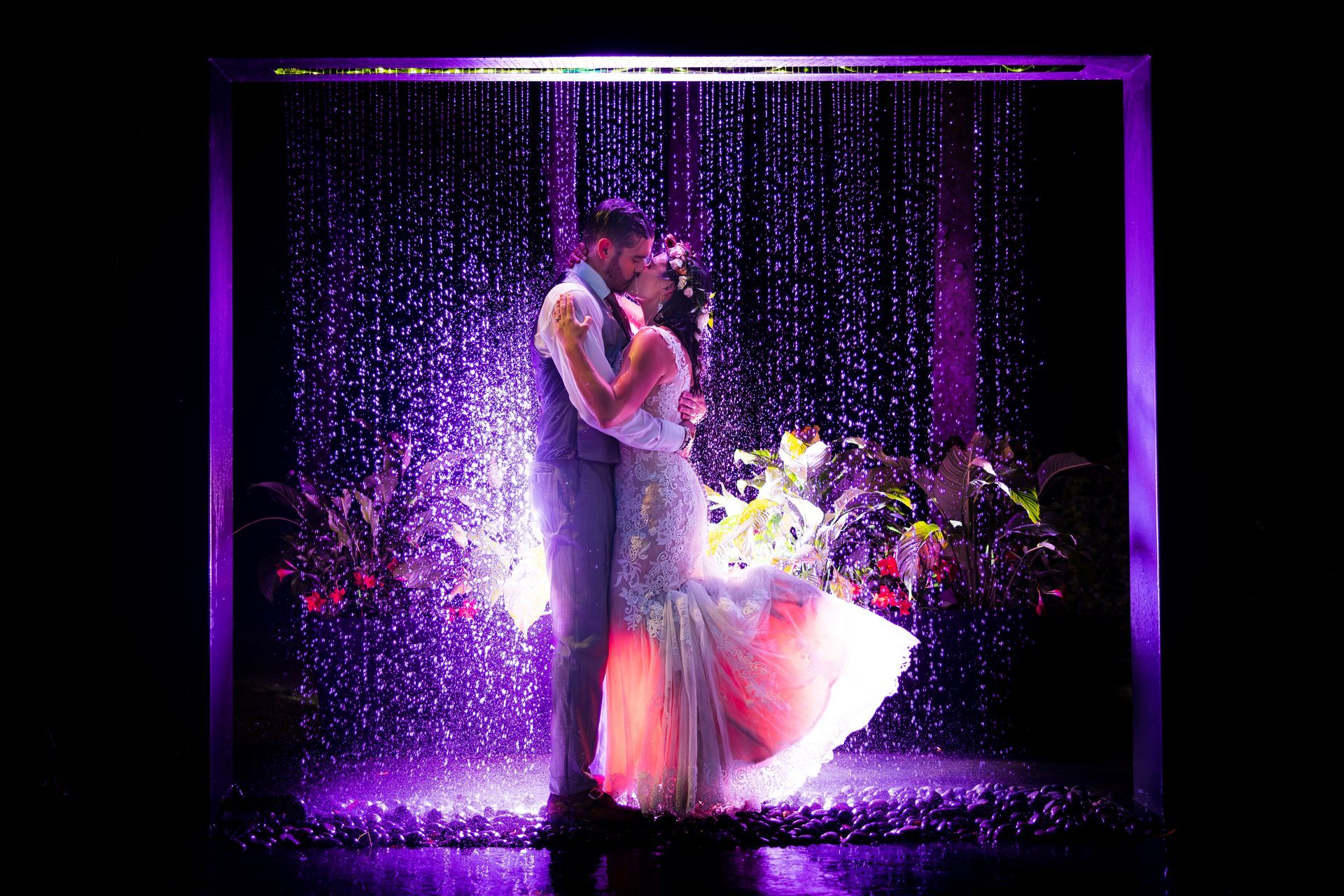 Couple embracing on a purple-lit stage with sparkling lights and a flowing dress
