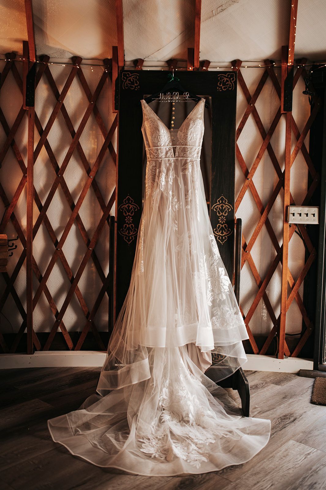 White wedding dress displayed on a mannequin in an ornate showroom, with a long lace train.