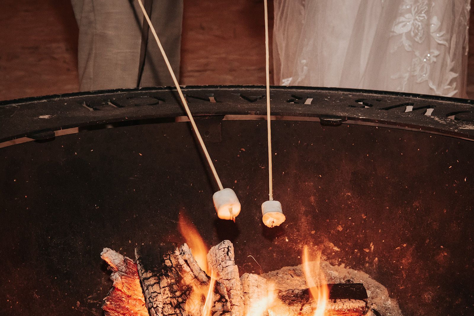 Marshmallows roasting over a campfire inside a black fire pit