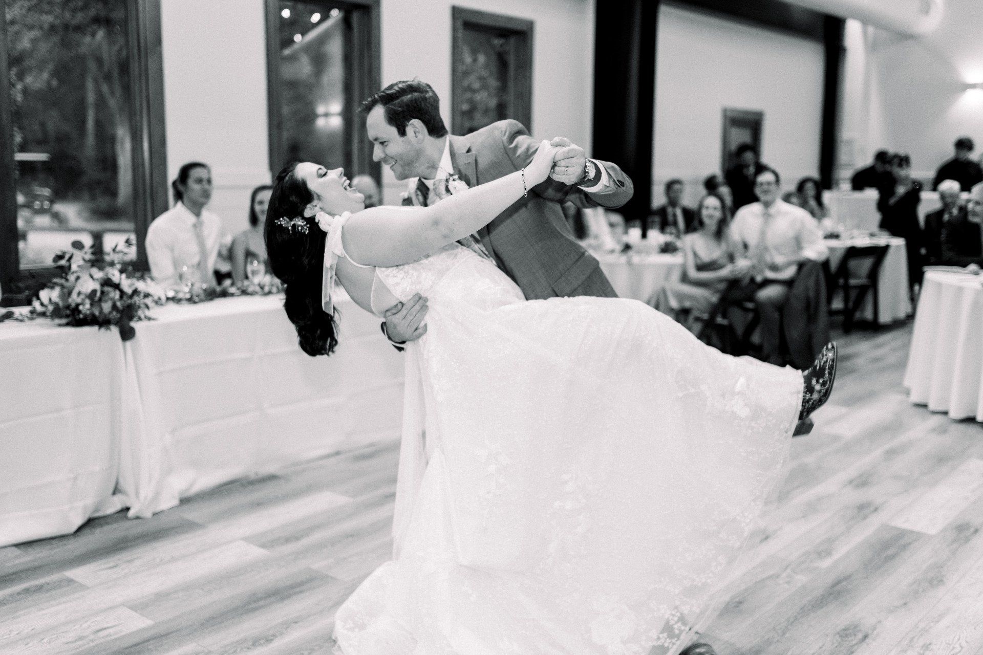 Bride and groom dancing at a wedding reception, dipping under warm indoor lighting