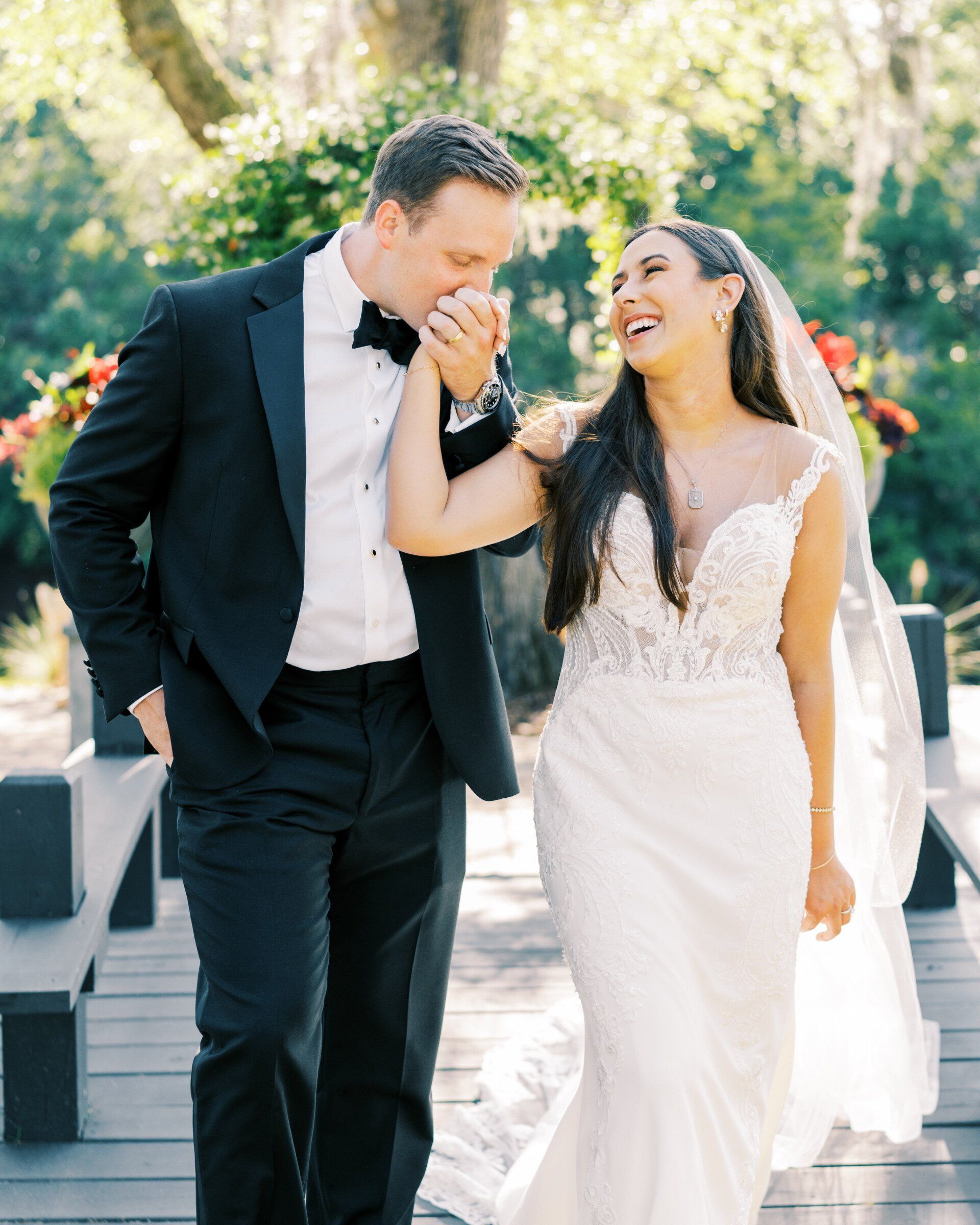 Bride and groom walking outdoors, smiling and laughing in formal wedding attire.