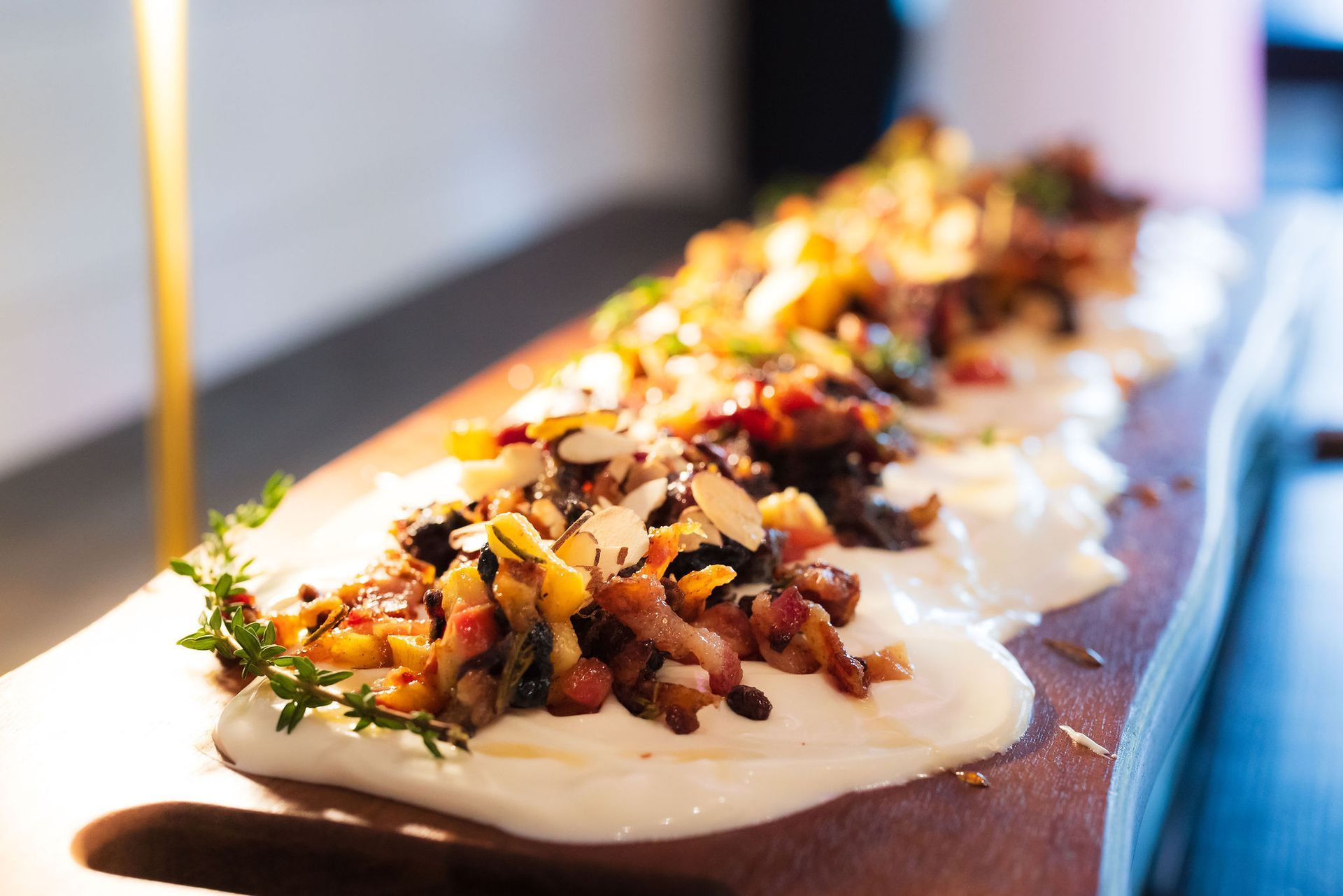 Platter of colorful appetizers topped with sauce and herbs on a wooden board