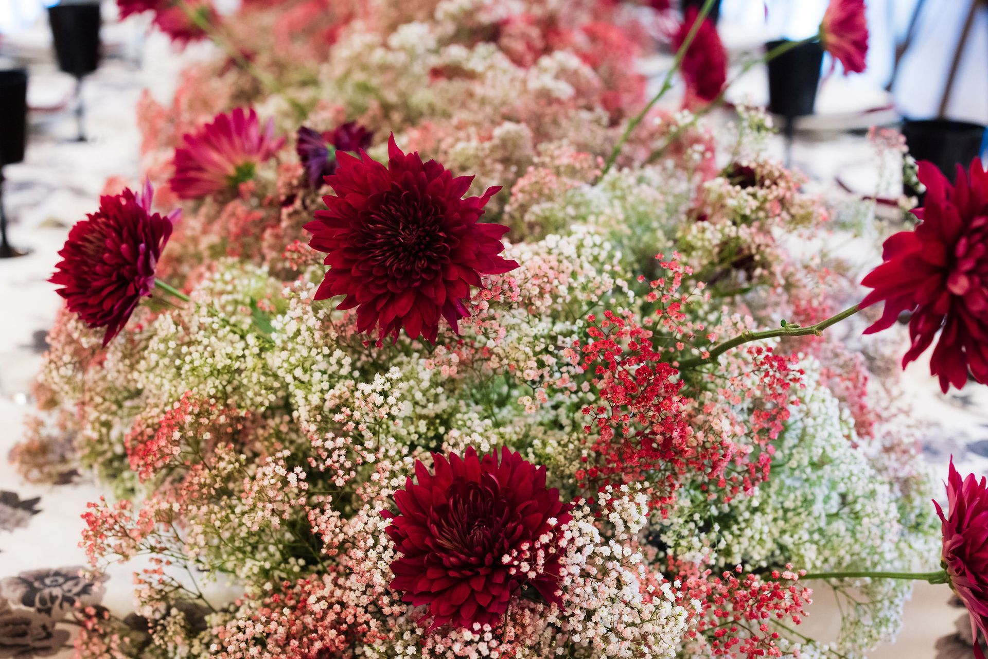 Red and white floral arrangement with burgundy blooms and baby’s breath flowers