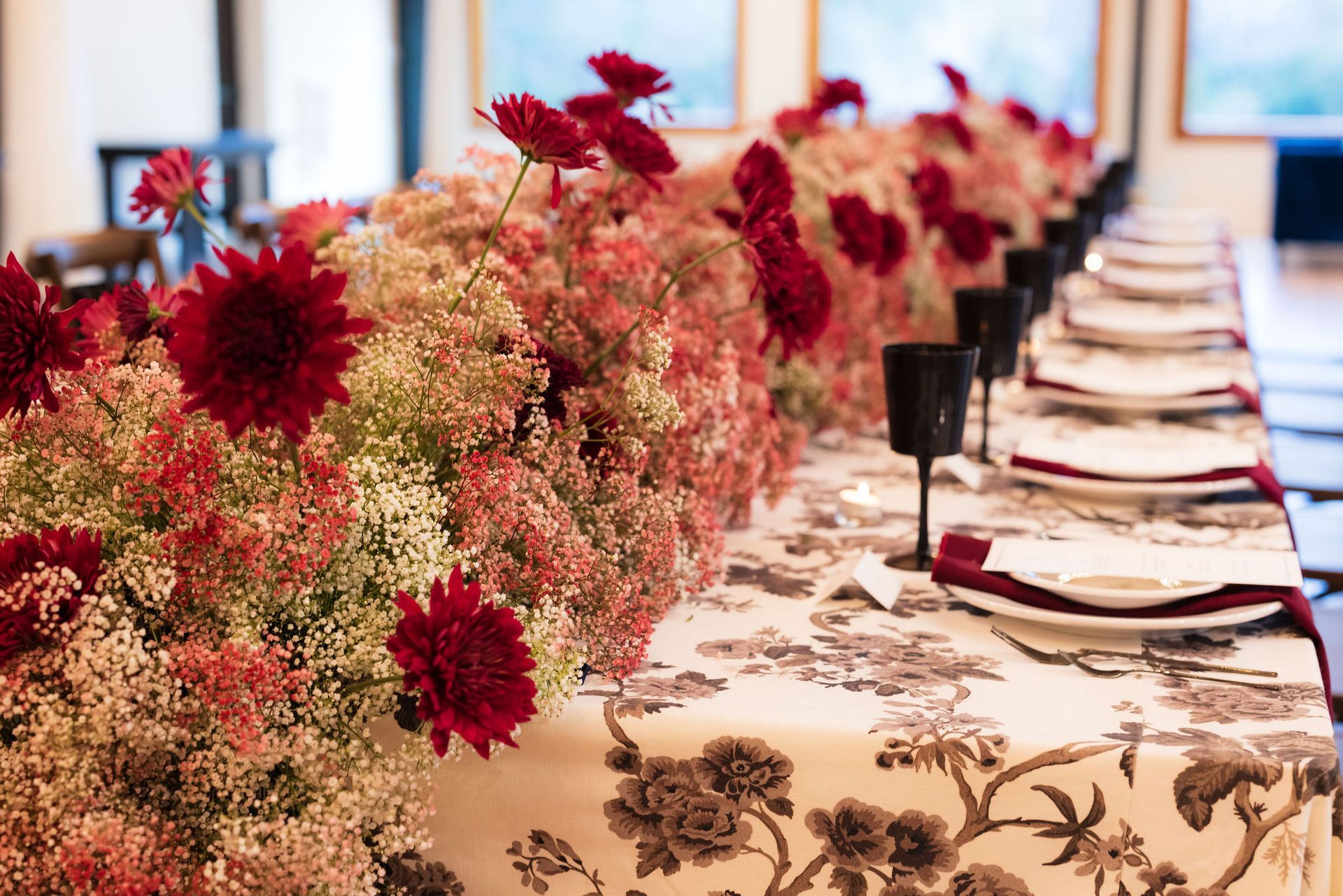 Long banquet table with floral centerpiece and place settings in a bright room