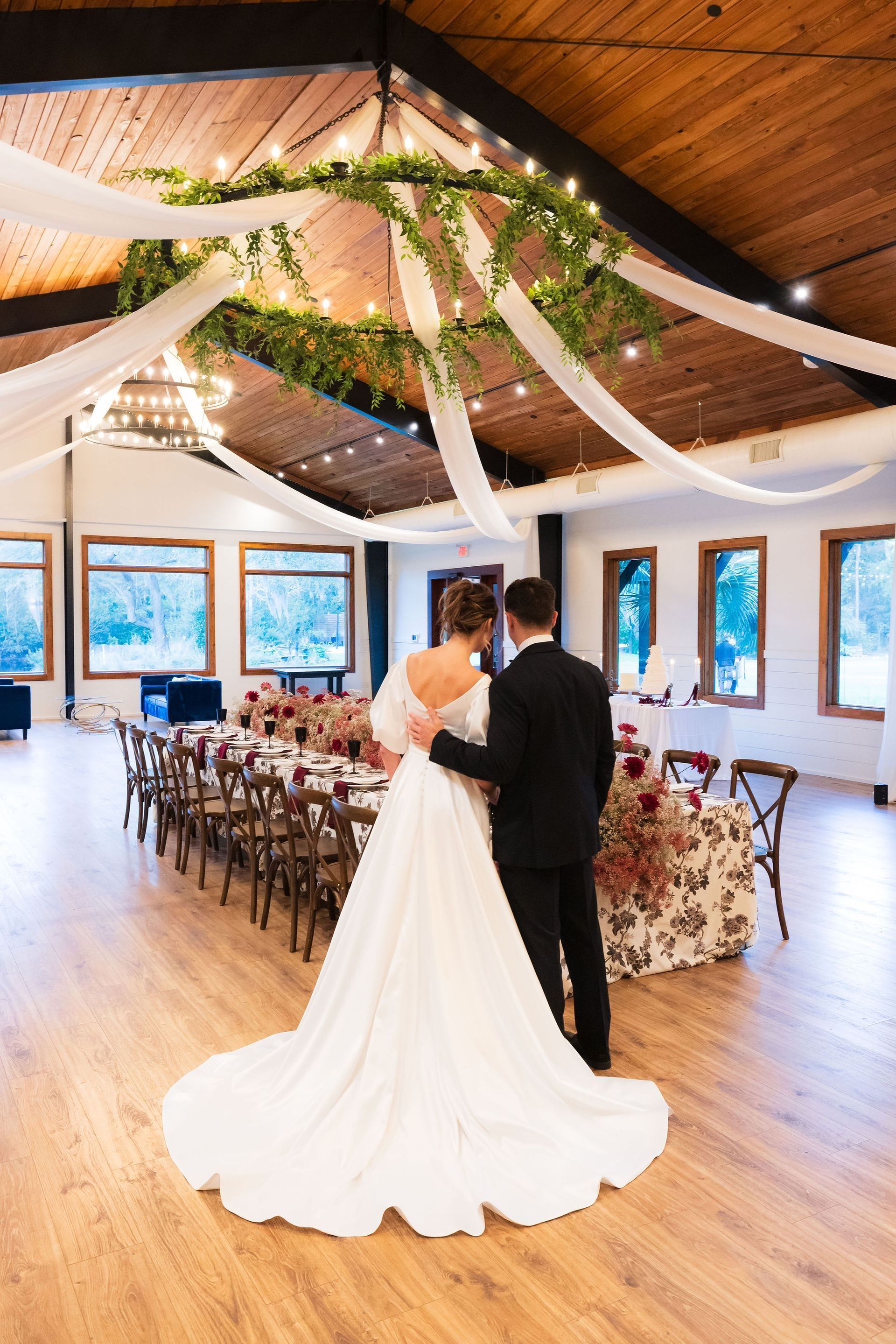 Wedding couple dancing in a decorated reception hall with white drapes and a floral arch