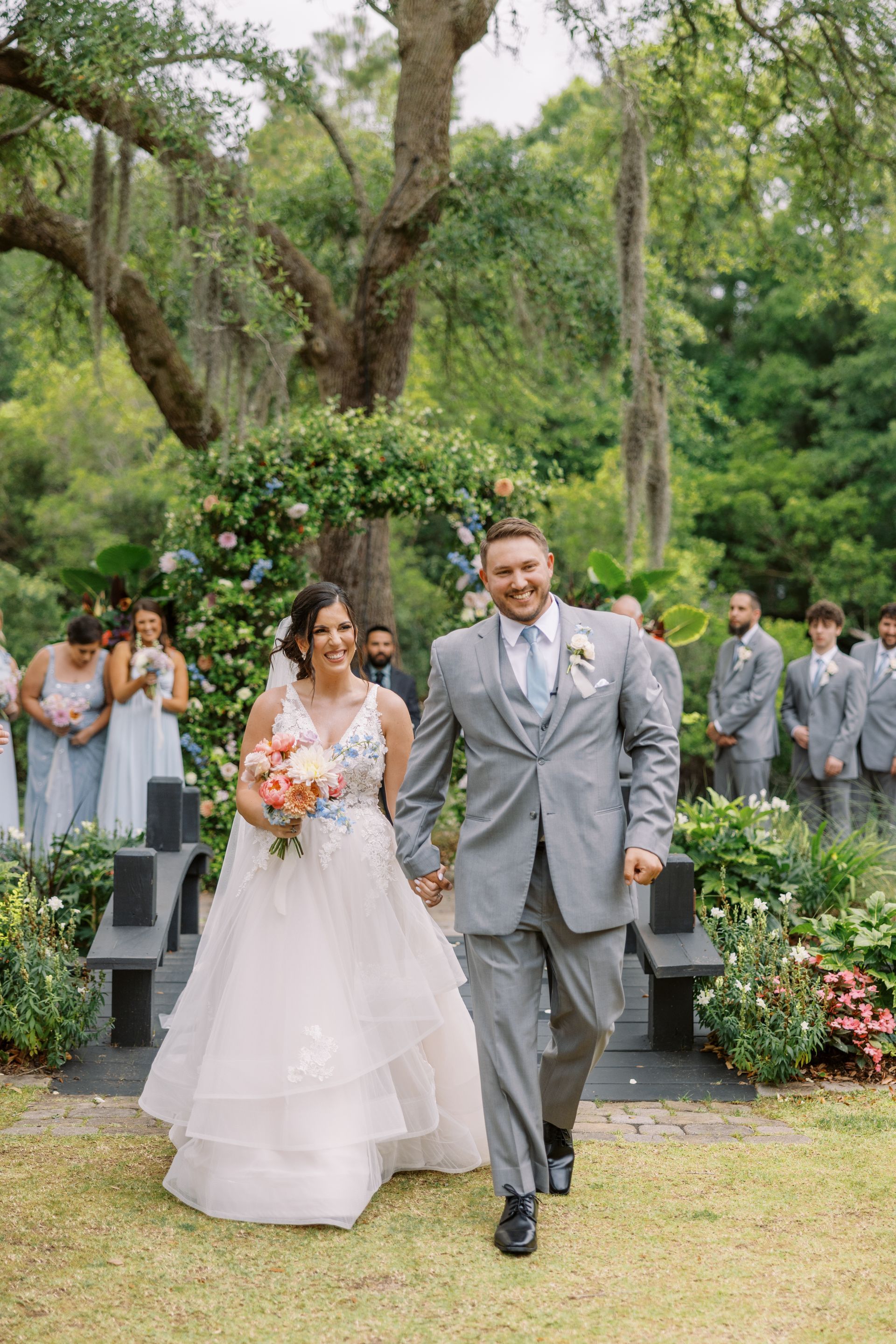 Bride and groom walking down an outdoor aisle at a garden wedding