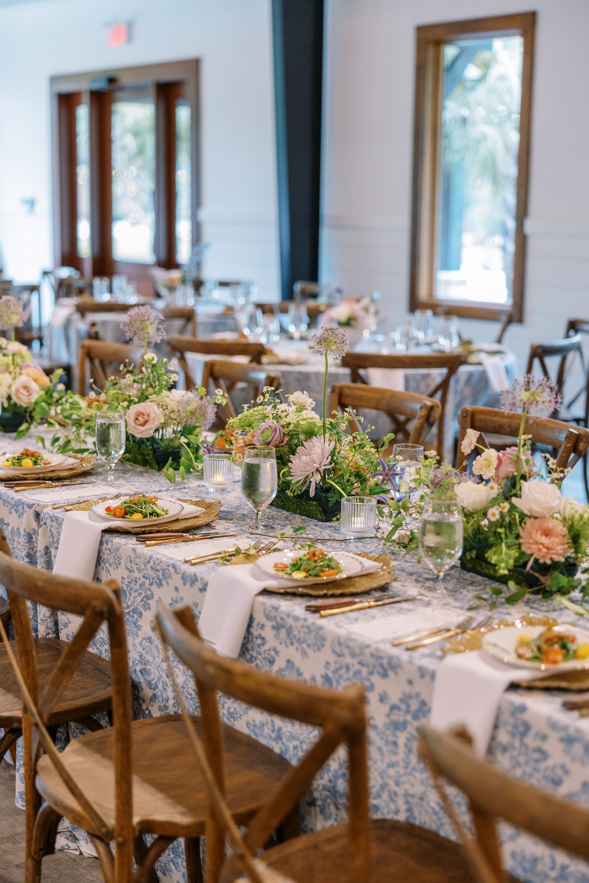 Elegant banquet tables with floral centerpieces and wooden chairs in a bright dining room