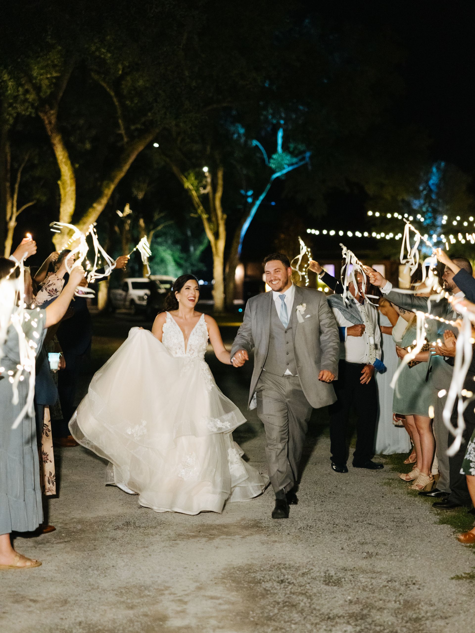 Bride and groom walking under sparklers at an outdoor nighttime wedding reception
