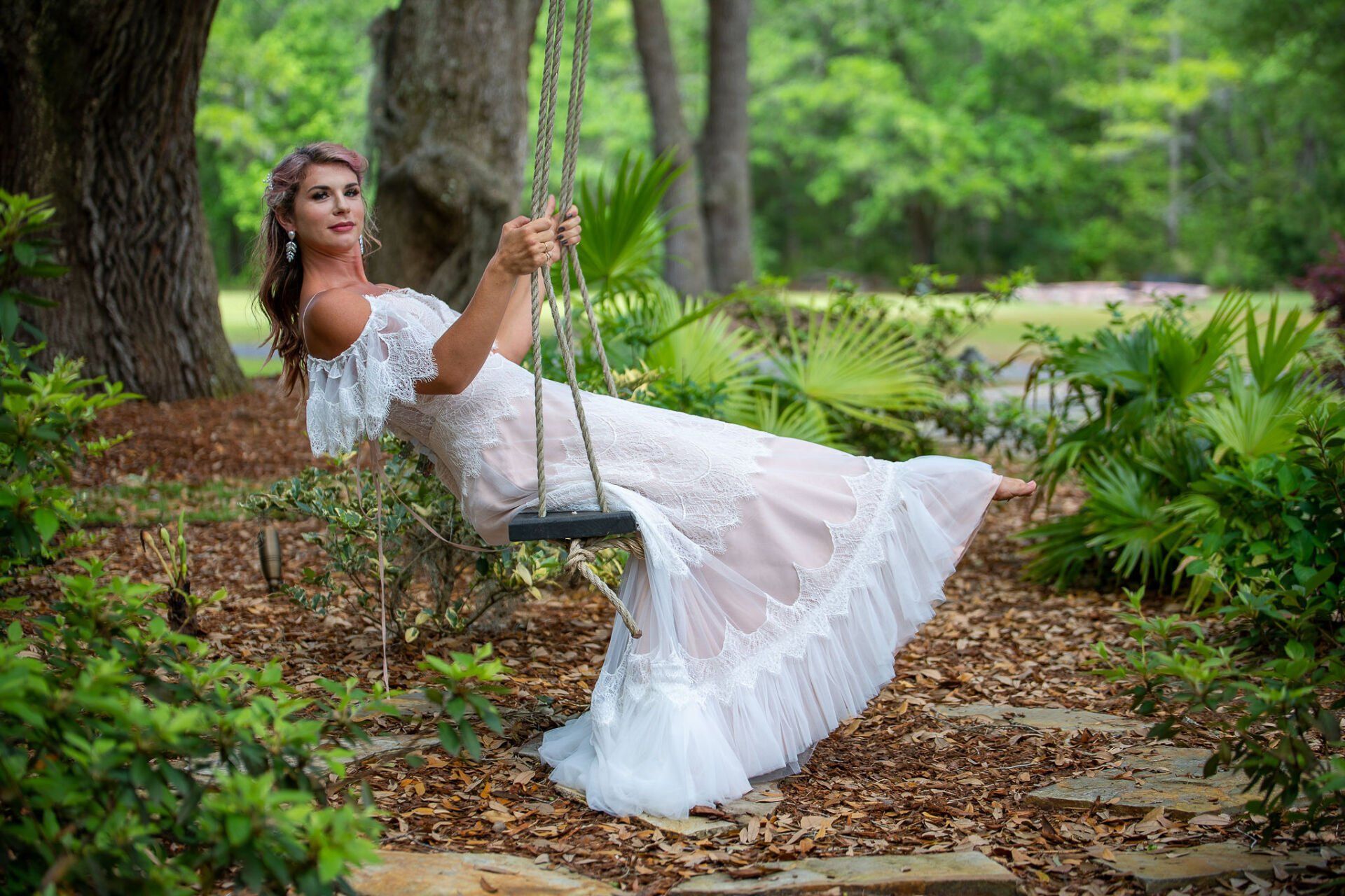 Woman in a white dress lounging on a swing in a leafy garden path