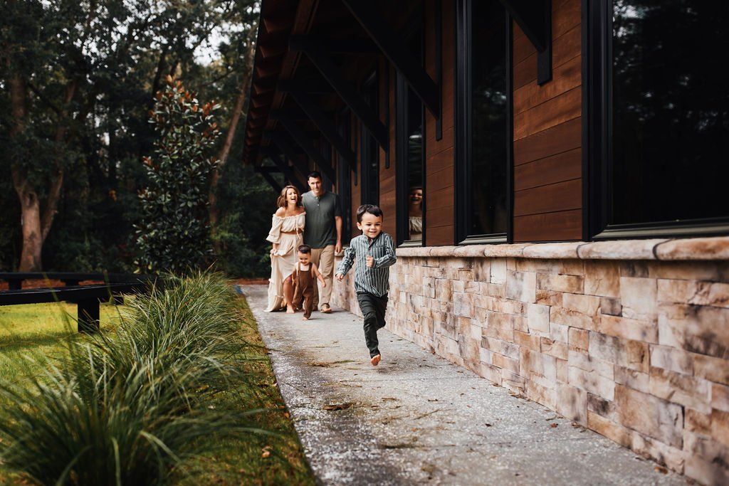 People walking along a gravel path beside a rustic wooden building in a wooded area