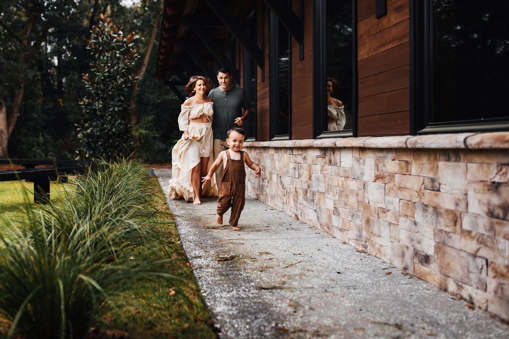 Family walking along a stone path beside a rustic building, with a child in the foreground.