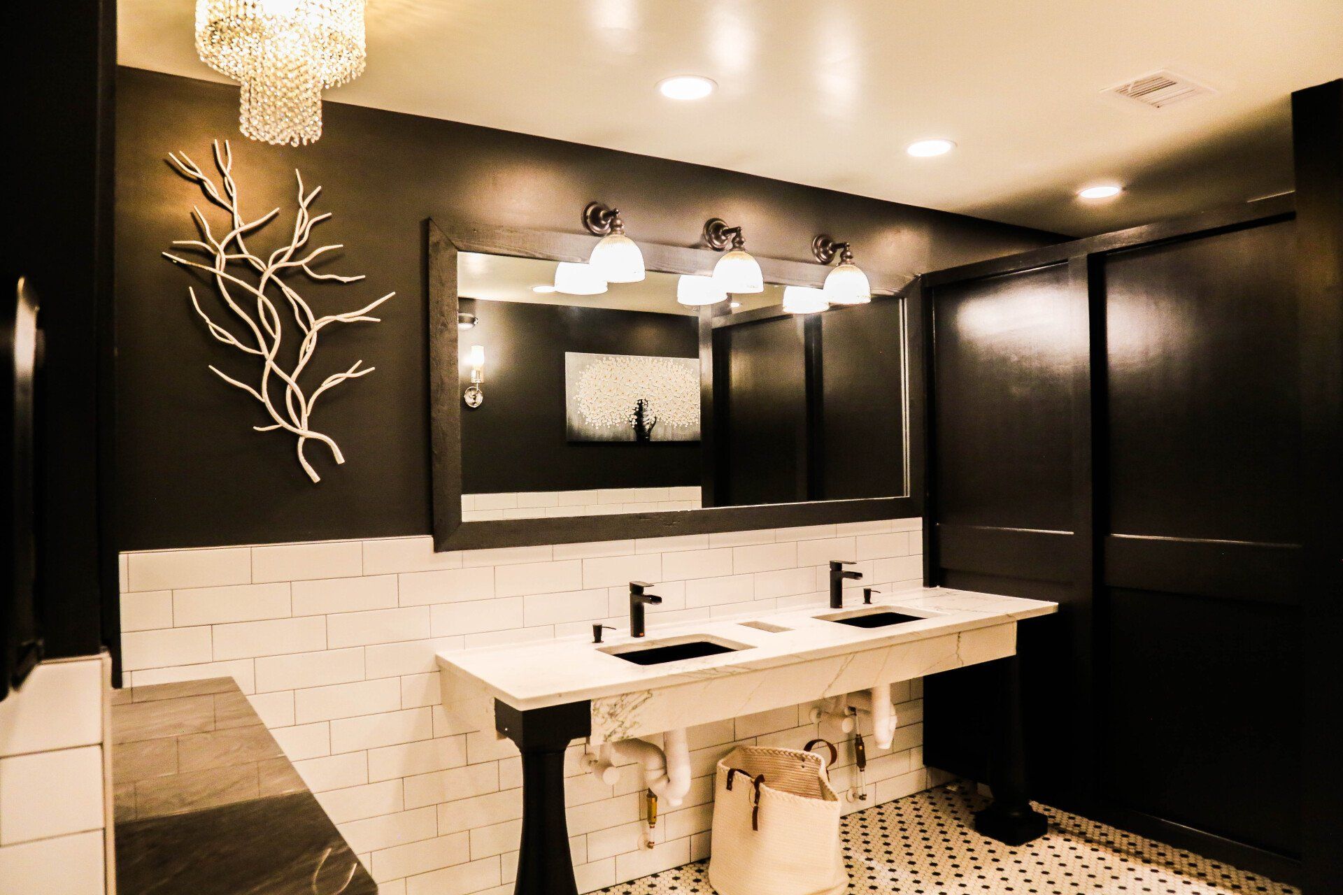 Modern bathroom with double sink vanity, large mirror, dark walls, and white mosaic tile accents