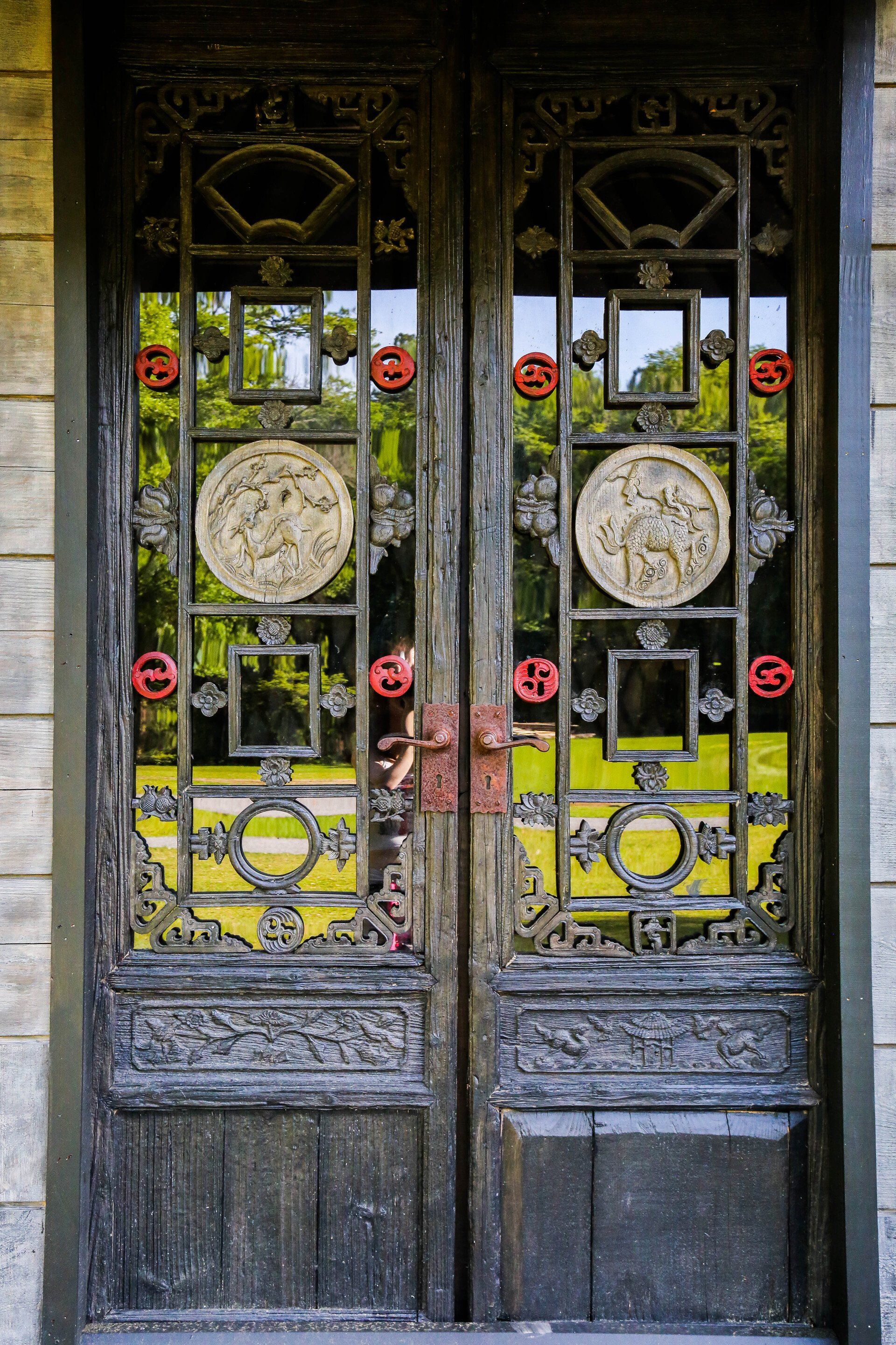 Ornate black double doors with yellow stained glass and circular rose designs at an entrance