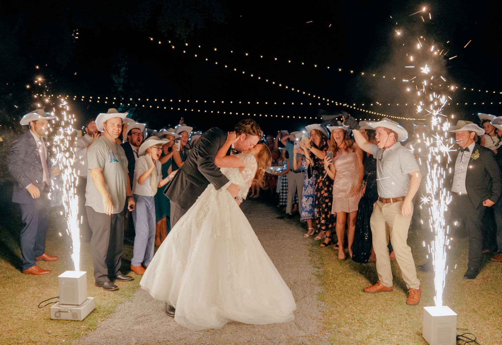 Wedding couple dancing under sparkling fountain fireworks at an outdoor evening reception