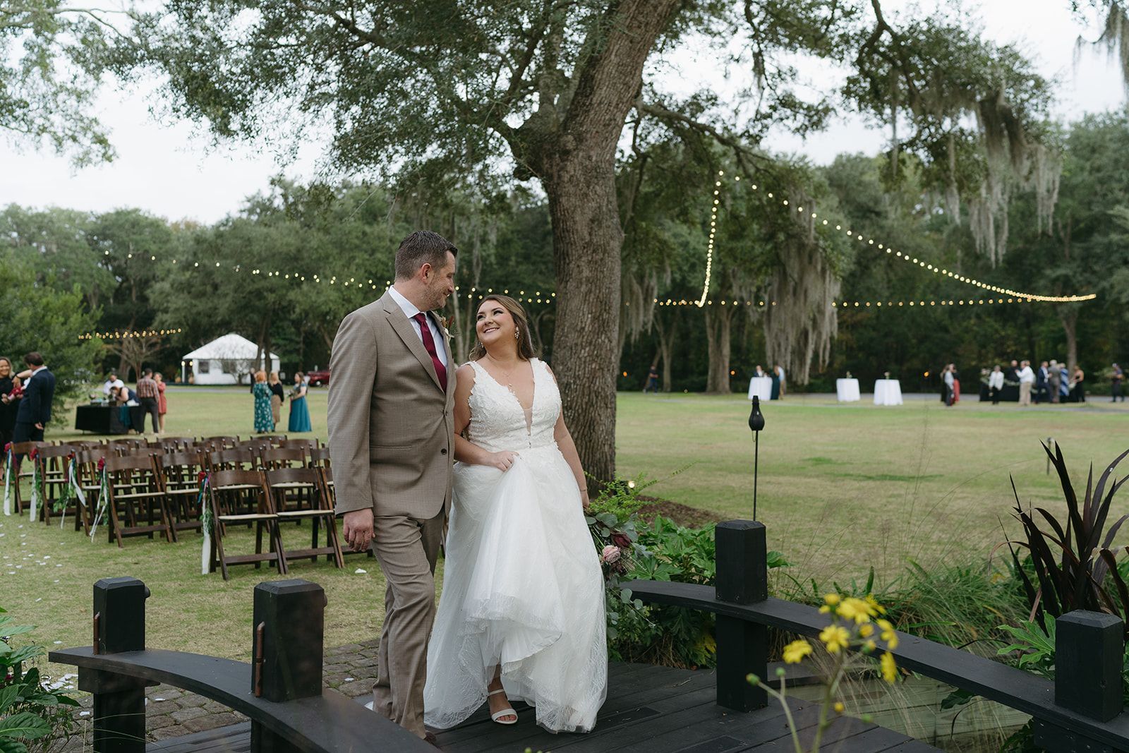 Couple in wedding attire standing together outdoors at a garden ceremony site.