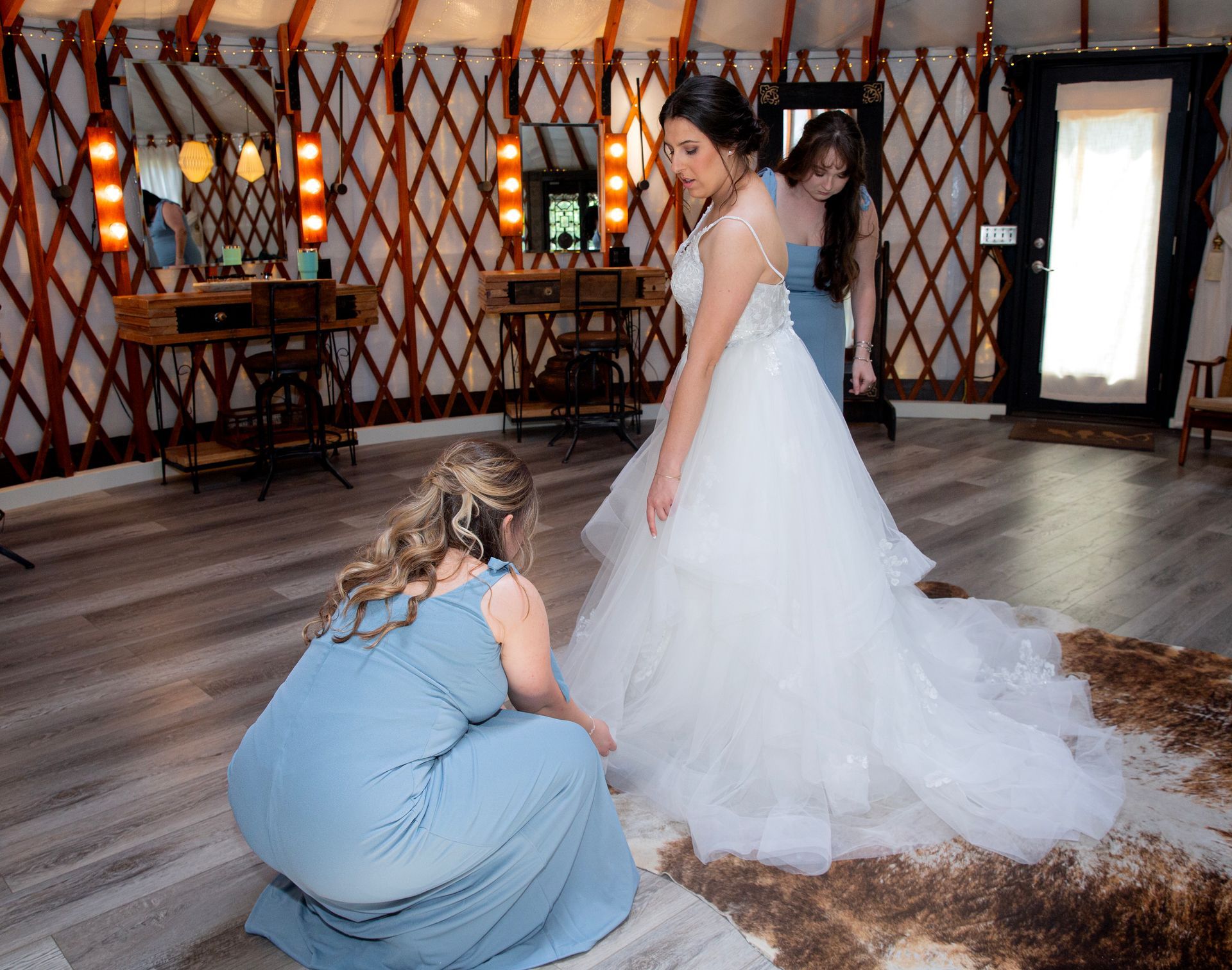 Woman in a white wedding dress with attendant in a blue gown inside a rustic hall