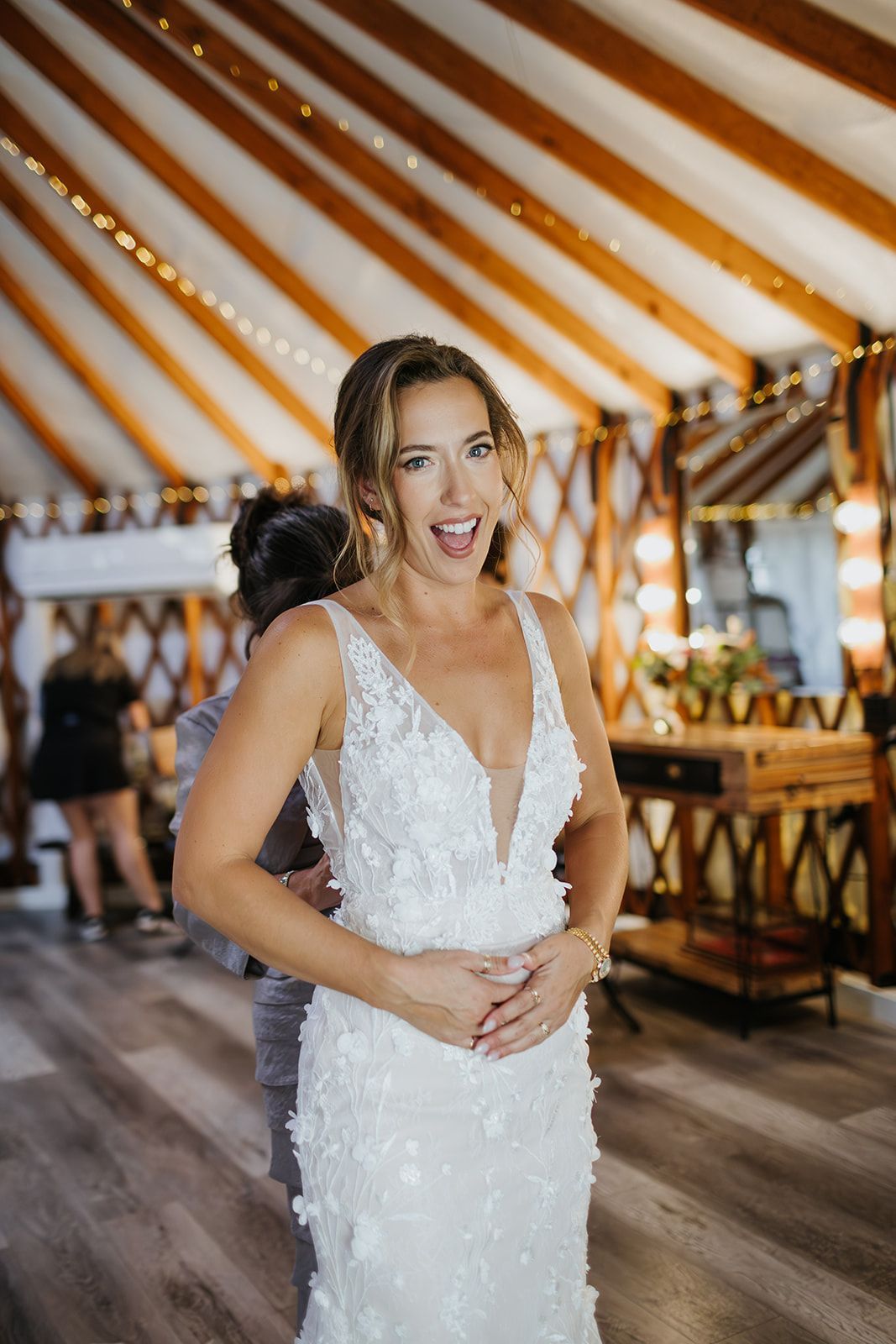 Woman in a white lace dress smiling in a decorated tent reception hall