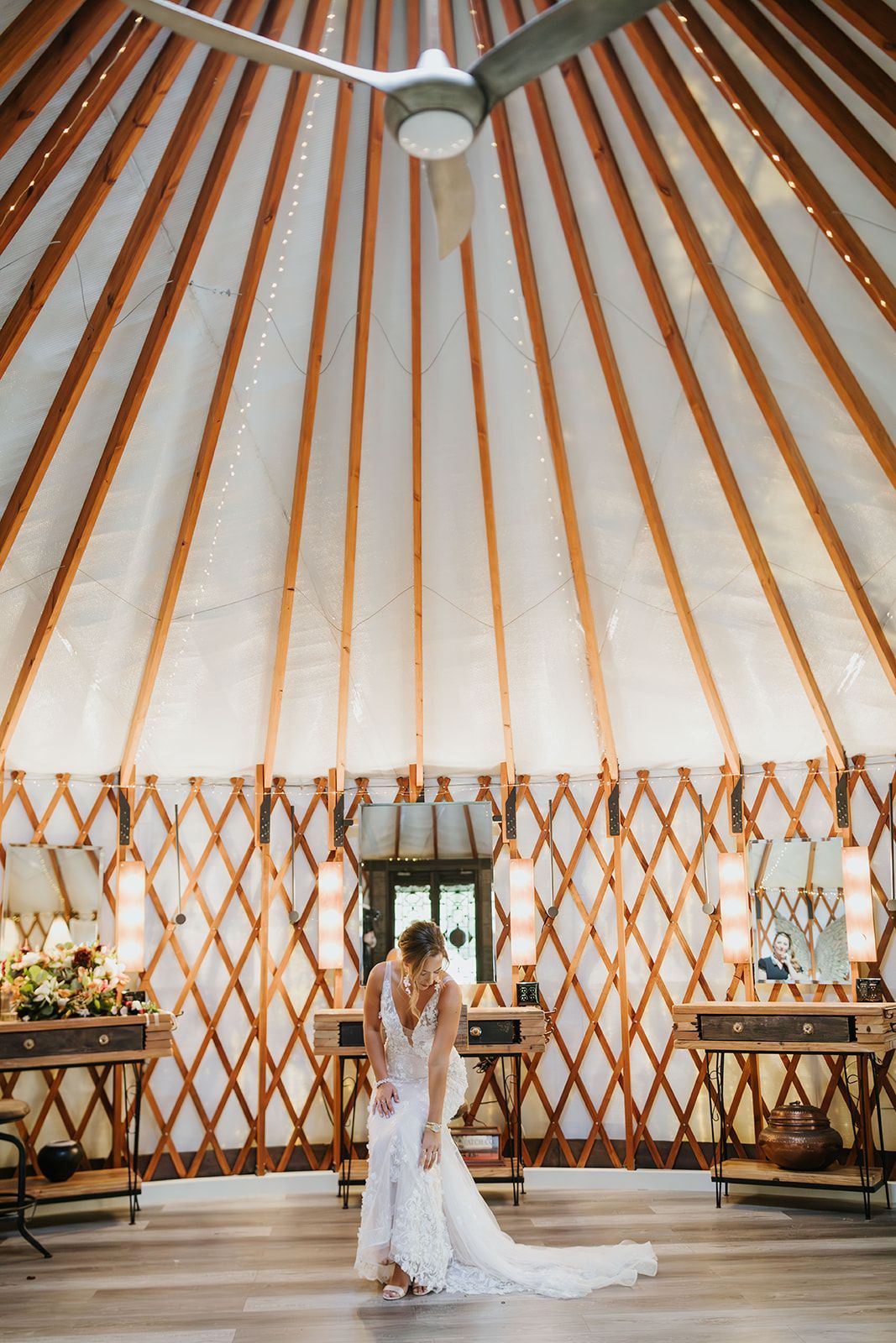 Bride and groom standing in a white yurt wedding venue with wooden beams and floral tables