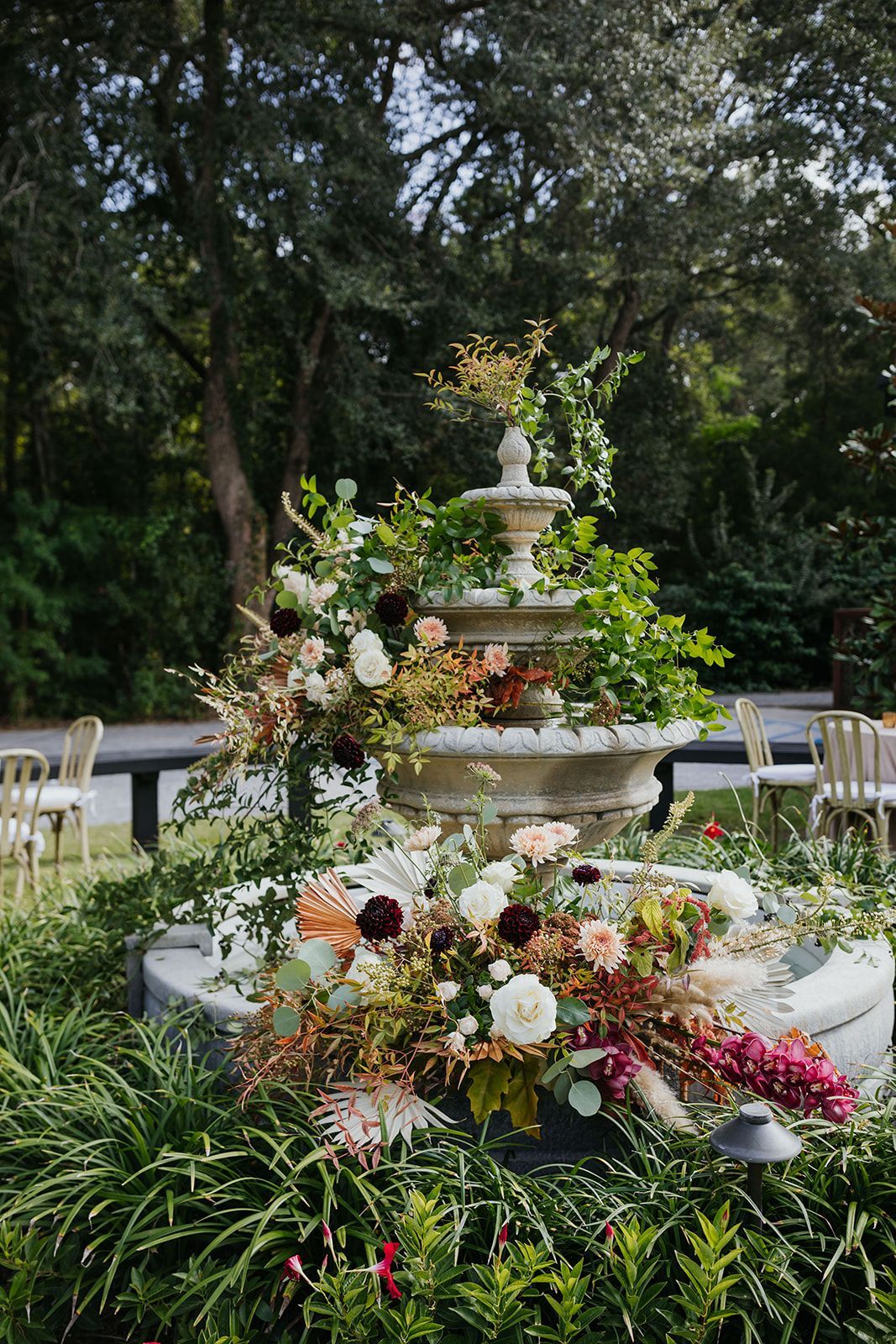 Flower-covered tiered fountain centerpiece in a garden setting