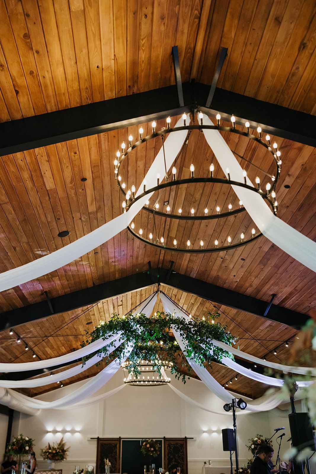 Decorated banquet hall ceiling with wood beams, hanging lights, and white draped fabric