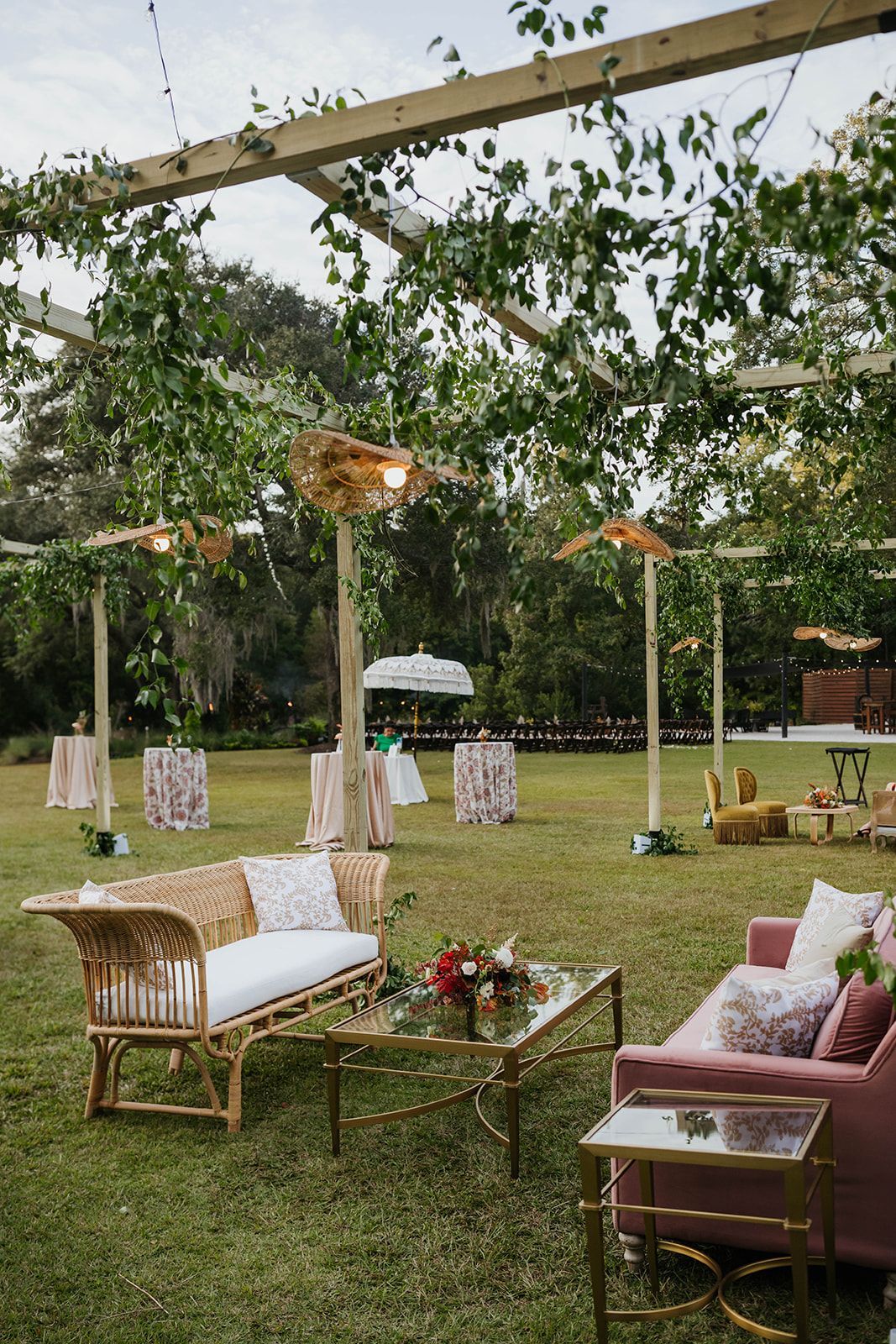 Outdoor lawn seating with wicker sofas and chairs under trees and canopies in a garden setting