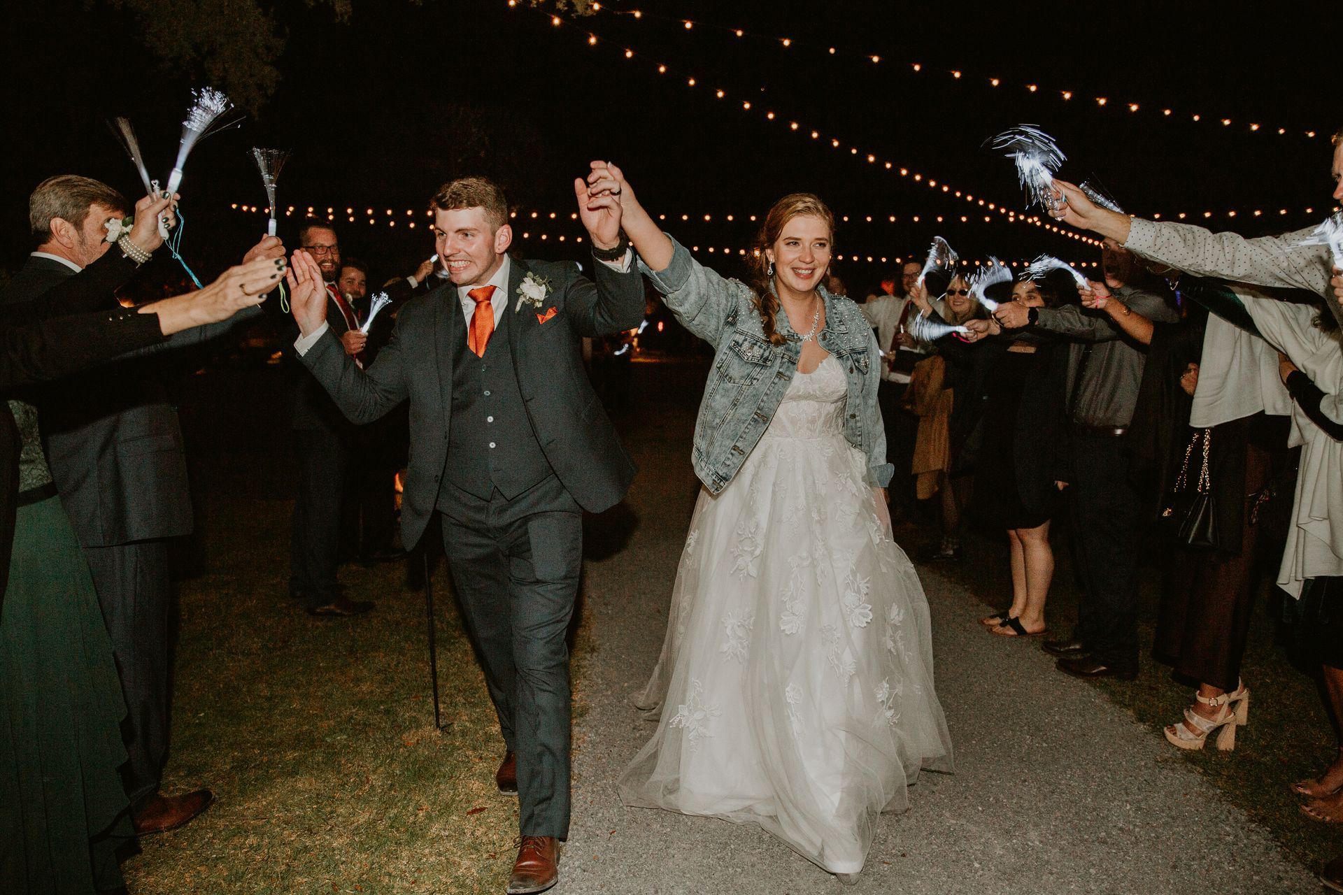 Newlyweds walking through a sparkler send-off at an outdoor nighttime wedding reception