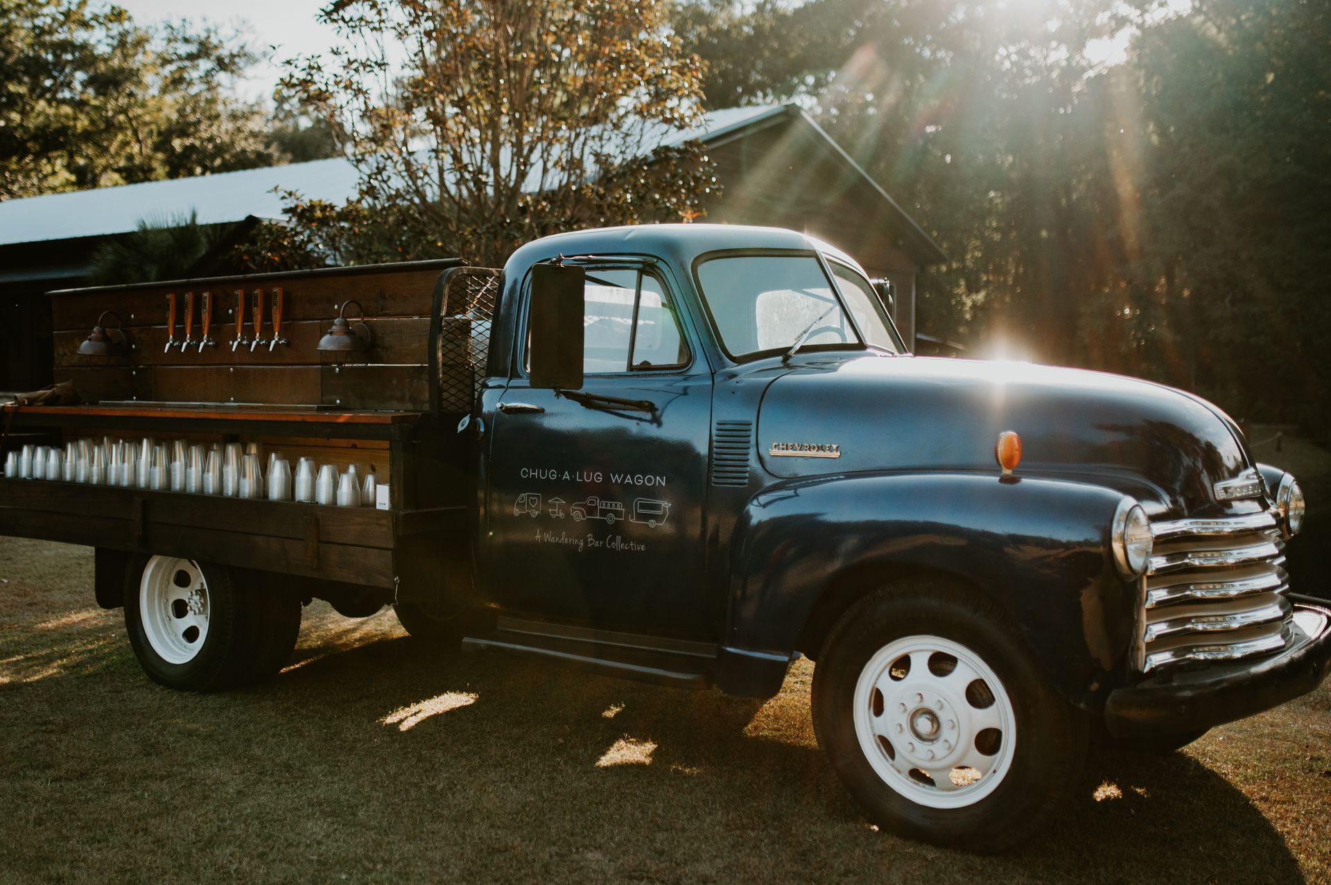 Vintage black pickup truck with wooden bed parked outdoors at sunset