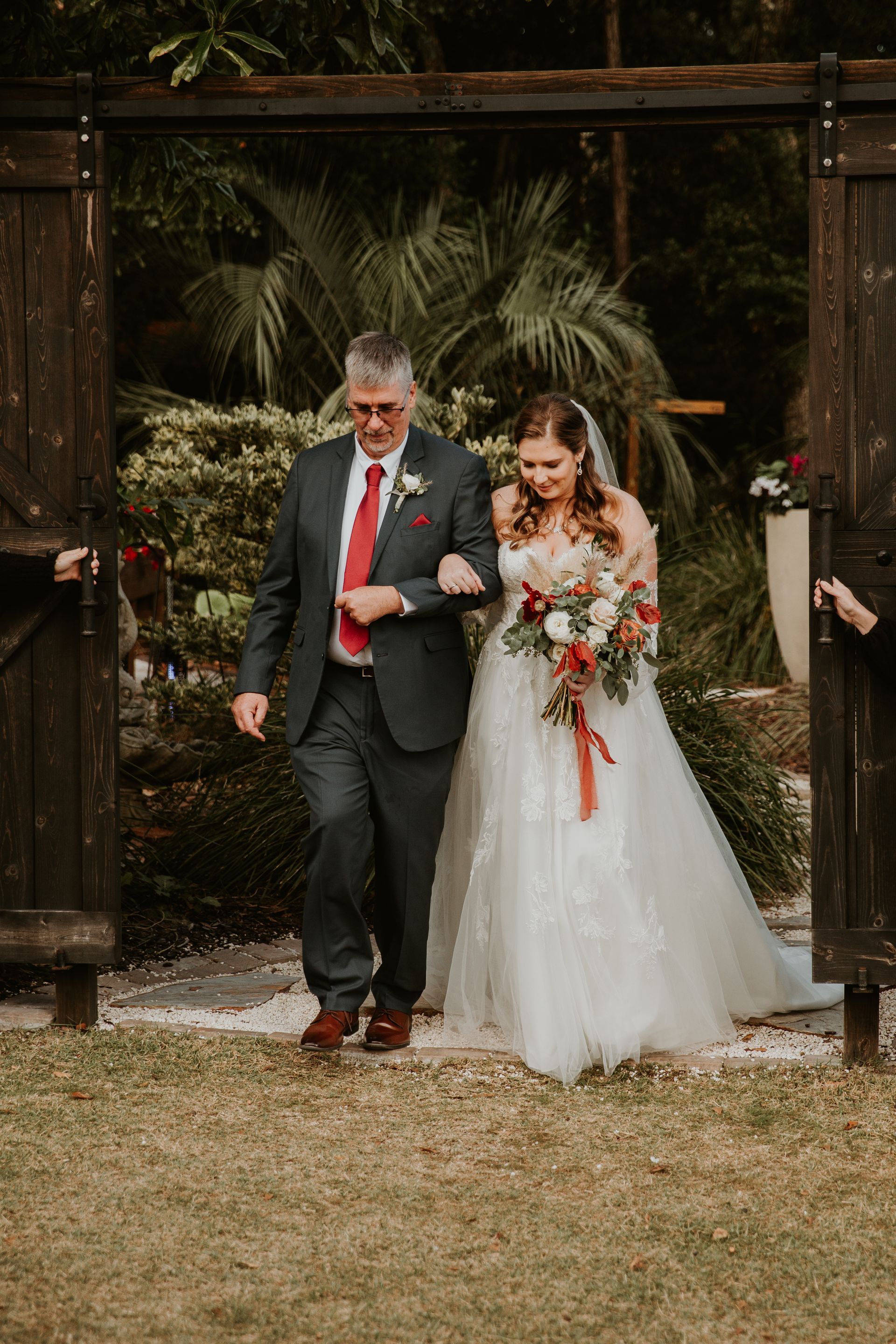 Bride and man walking under a floral arch in a garden ceremony