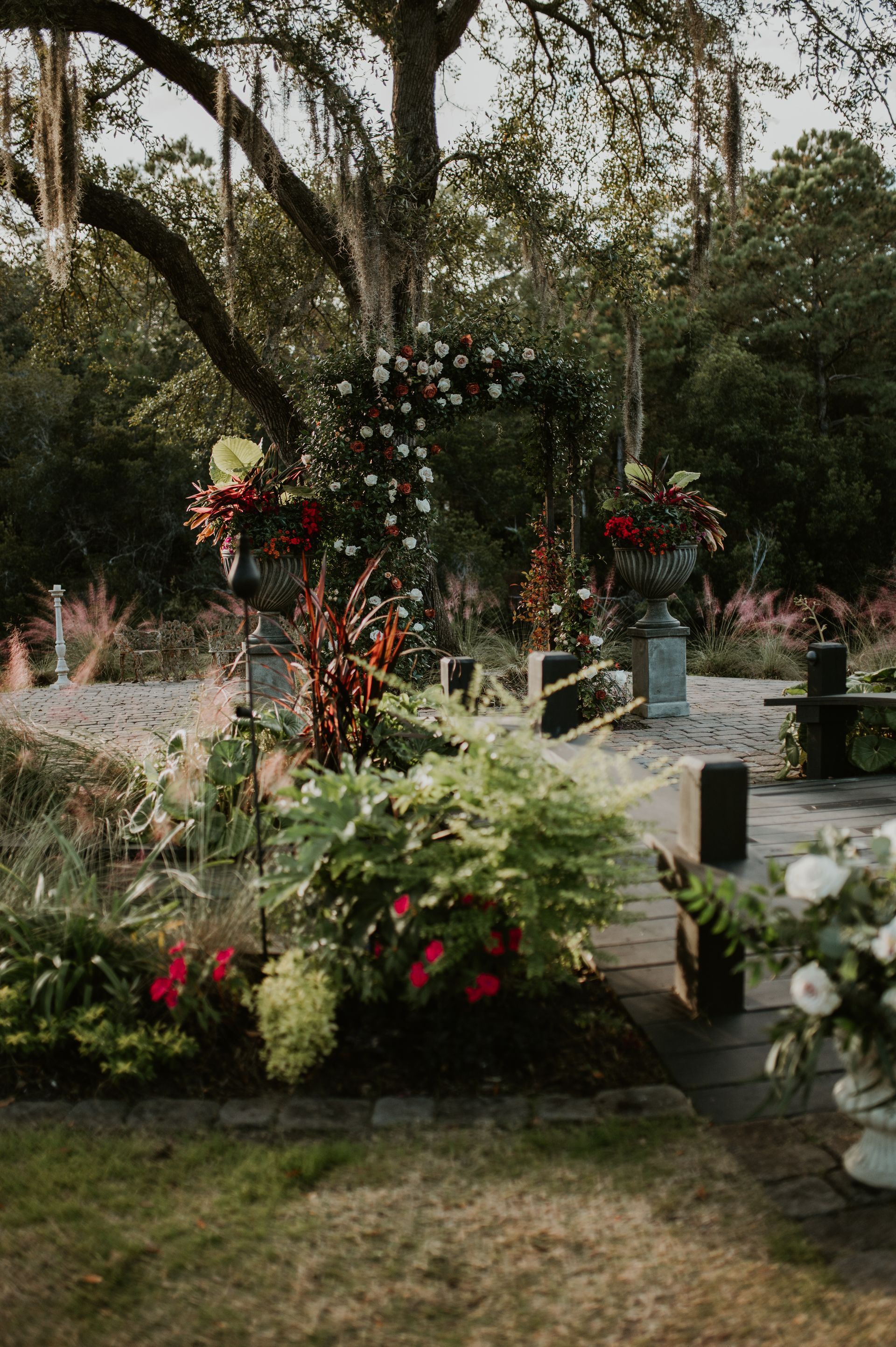 Flower-lined garden path with white and red blooms beneath a large tree