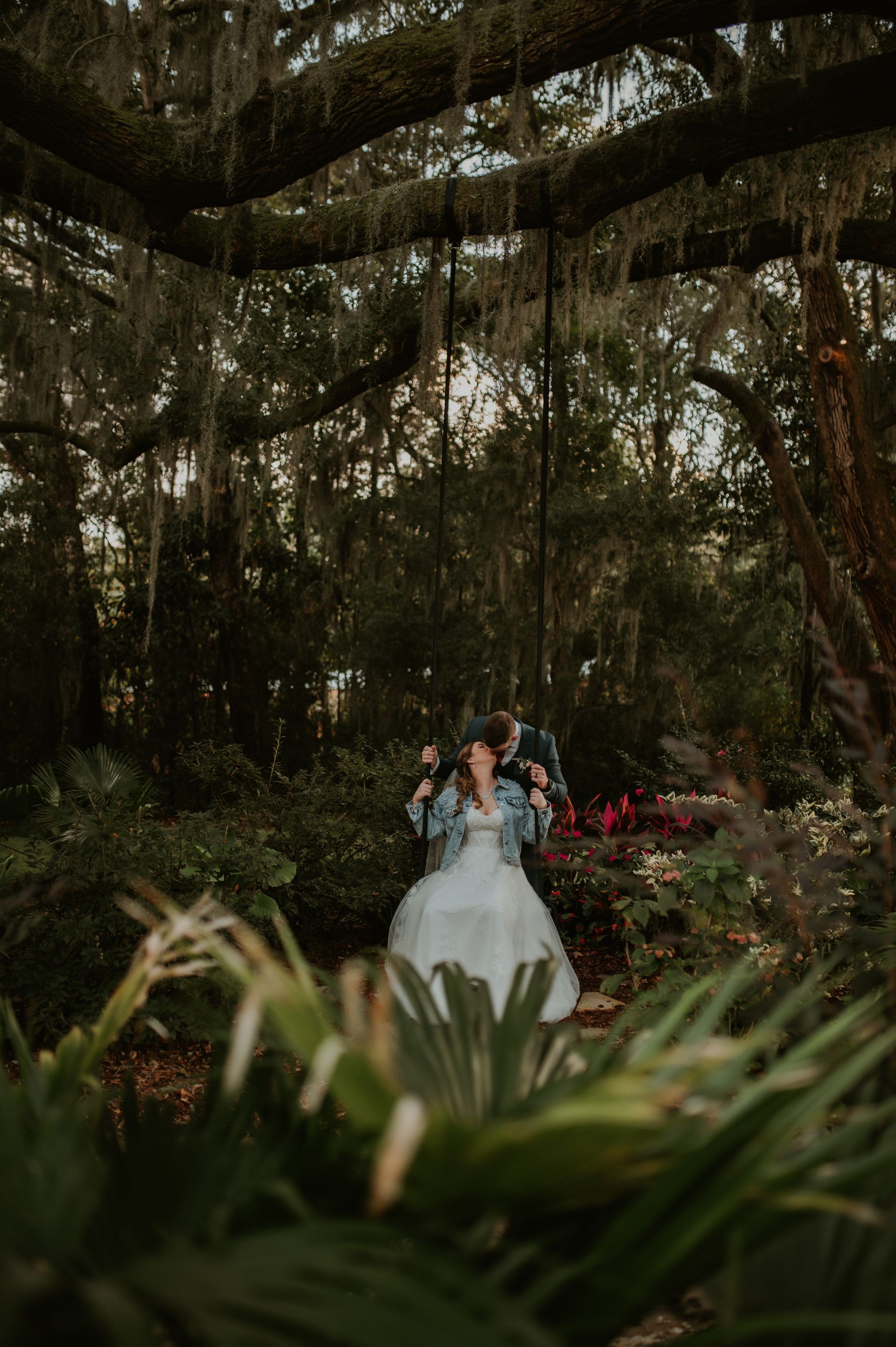 Bride and groom beneath hanging vines in a lush garden setting