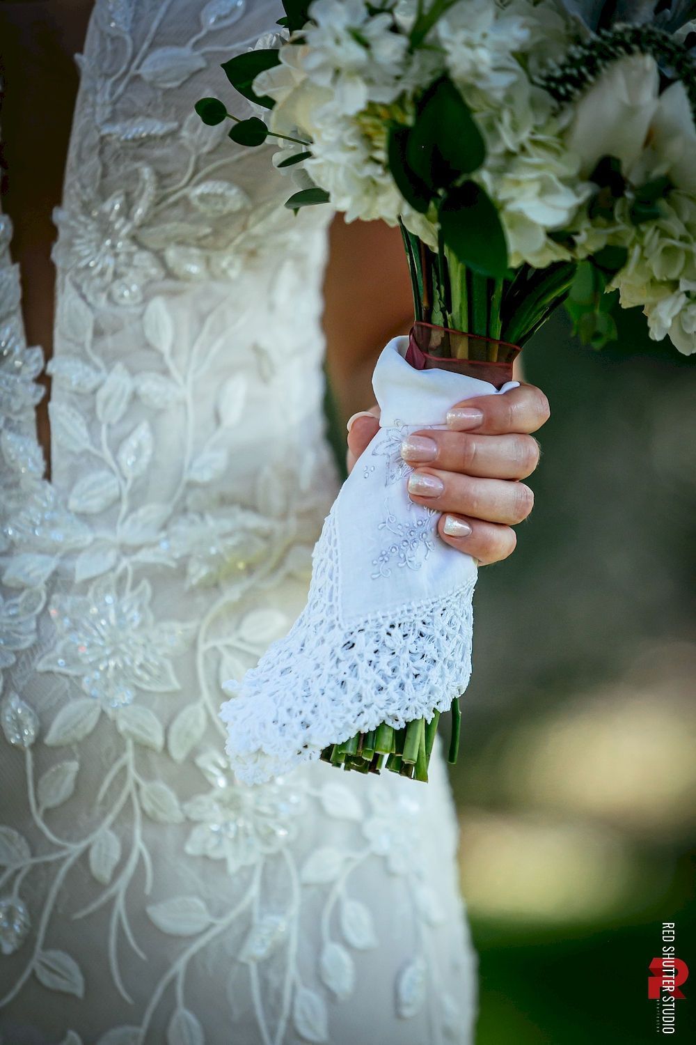 Bride in white lace dress holding a white floral bouquet close-up