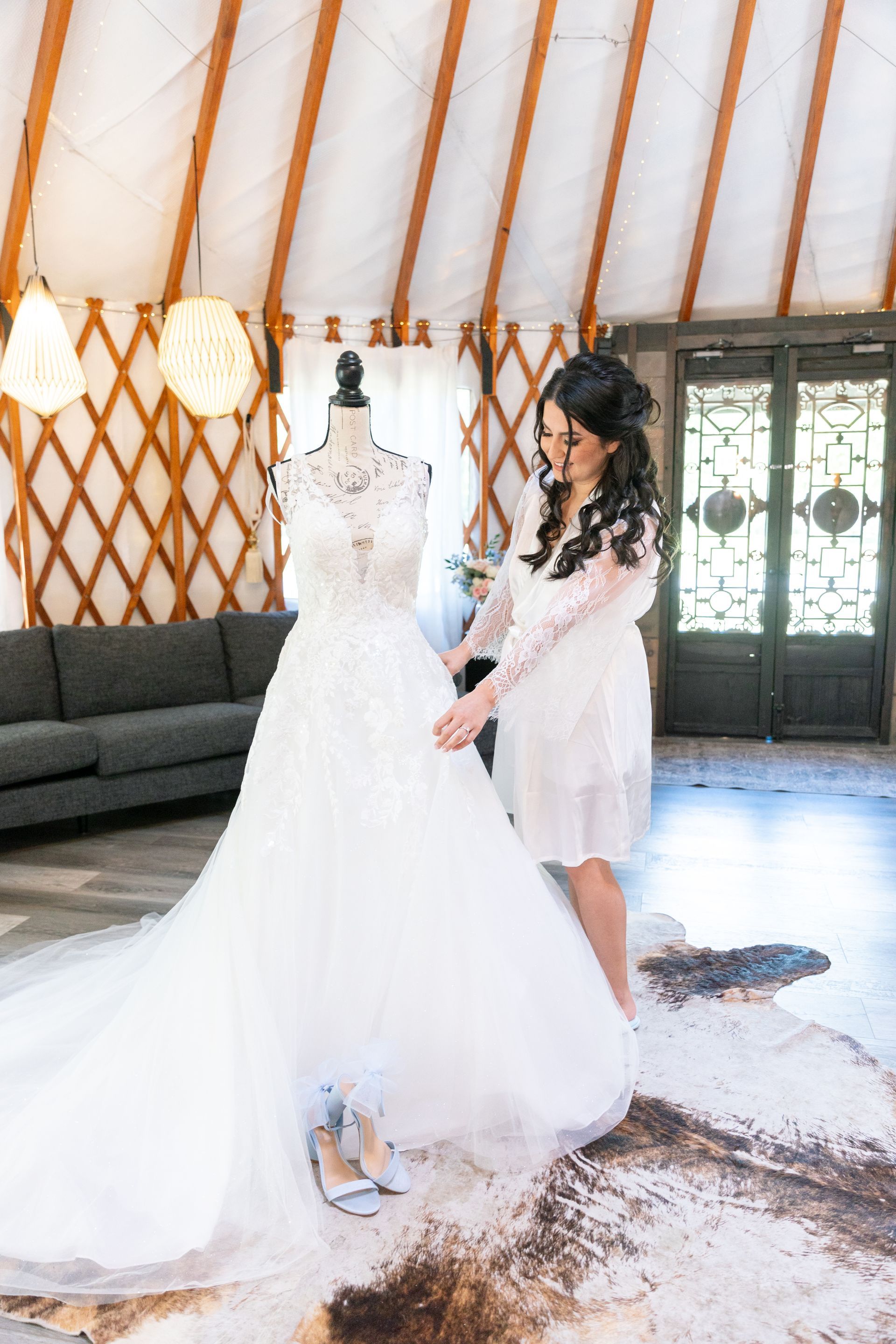 Bride adjusting a white wedding dress on a mannequin inside a rustic bridal studio
