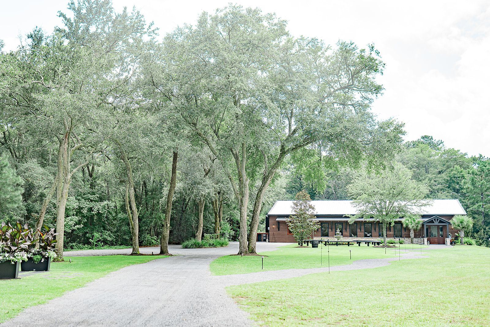 Gravel path through a grassy park toward a small wooden building under tall trees