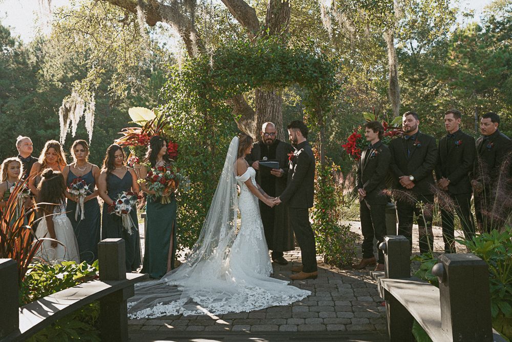 Bride and groom exchange vows in a garden wedding ceremony under a vine-covered arch.