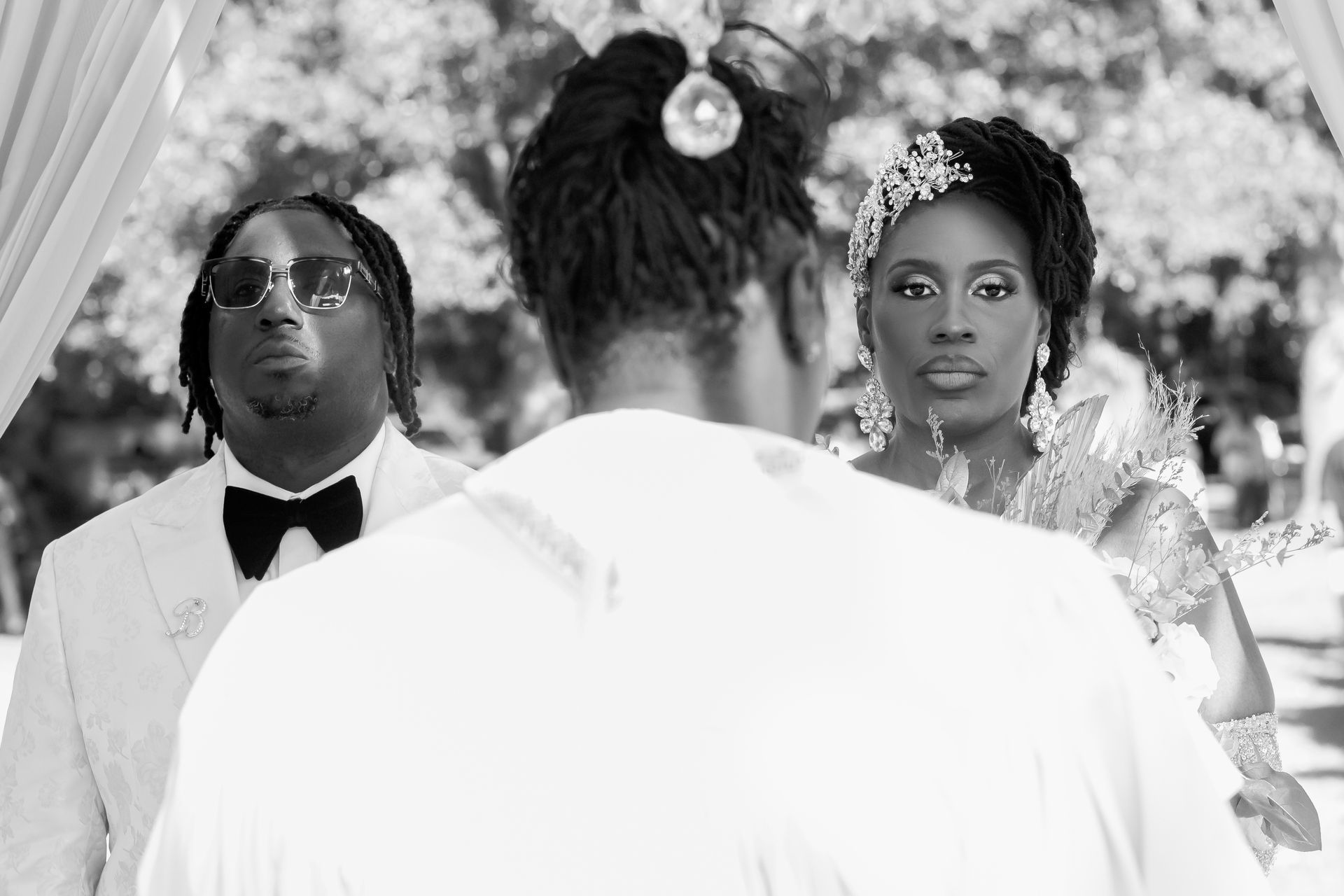 Bride and groom face an officiant during an outdoor wedding ceremony
