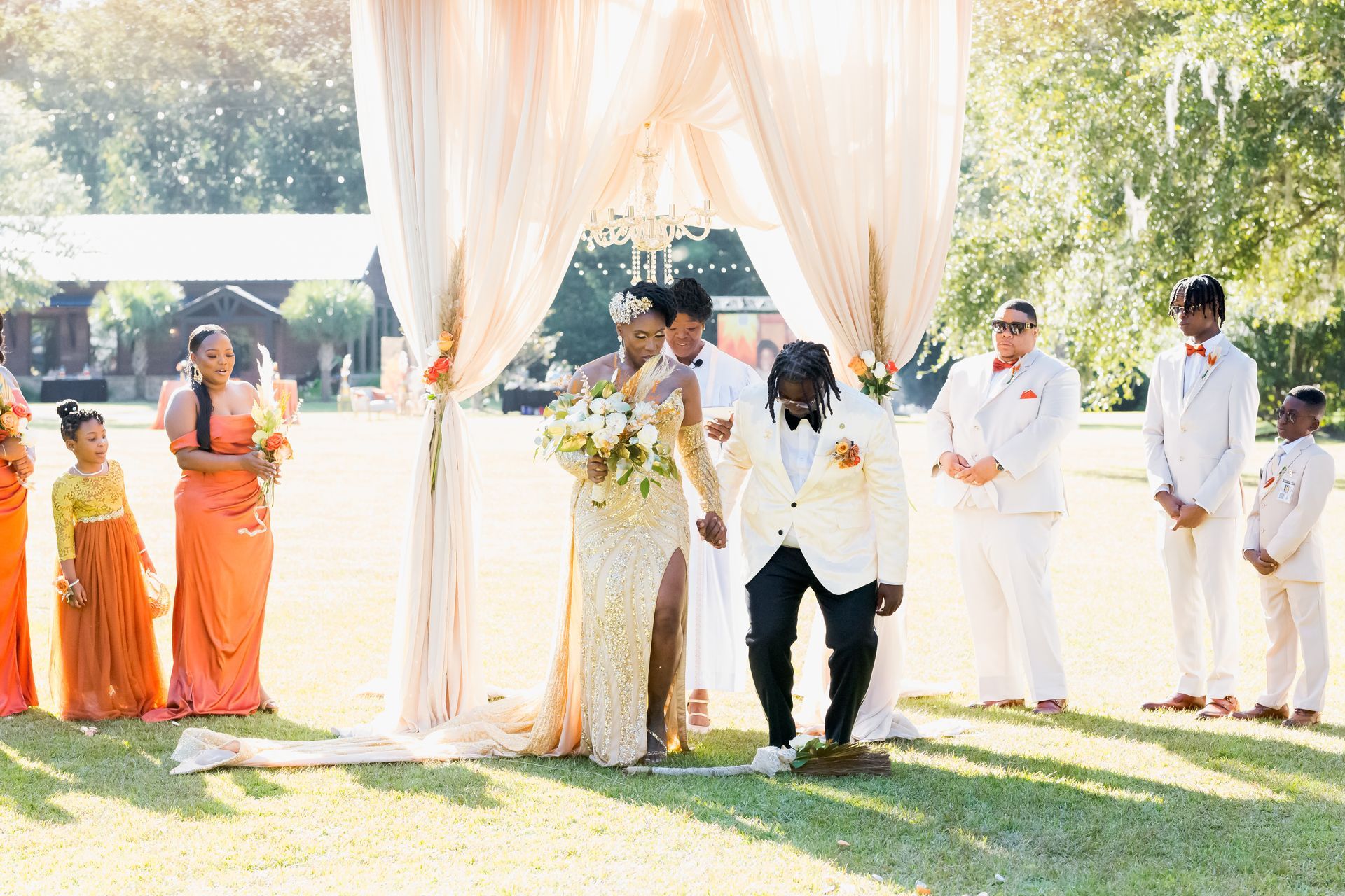 Outdoor wedding ceremony with bride and groom under a draped arch, attendants standing nearby