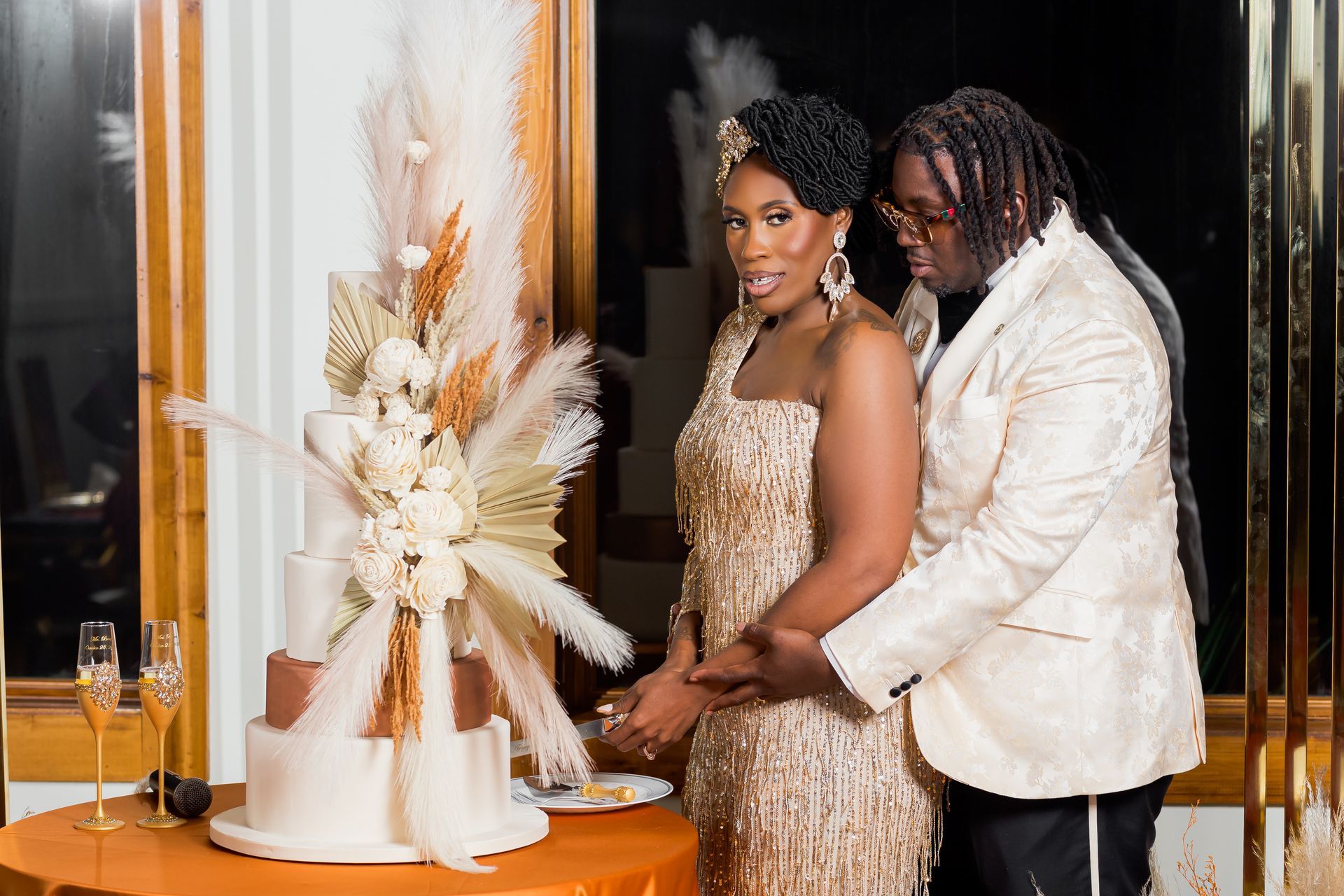 Couple in formal attire beside a white floral centerpiece at an elegant indoor event