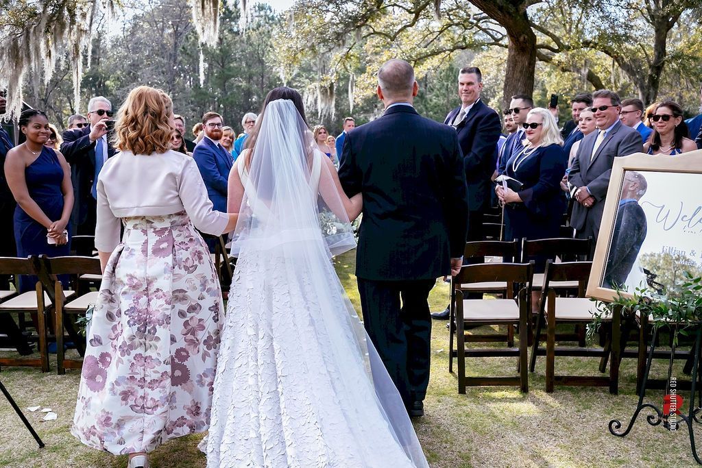 Bride and groom standing at an outdoor wedding ceremony facing guests under trees