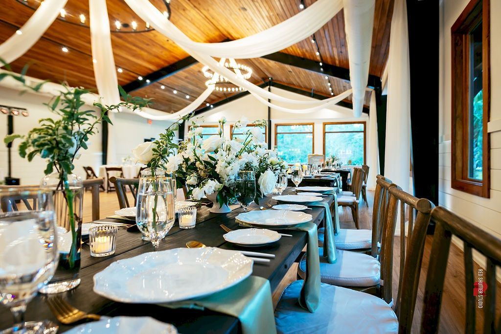Elegant dining room with white draped ceiling, floral centerpieces, and set tables by large windows