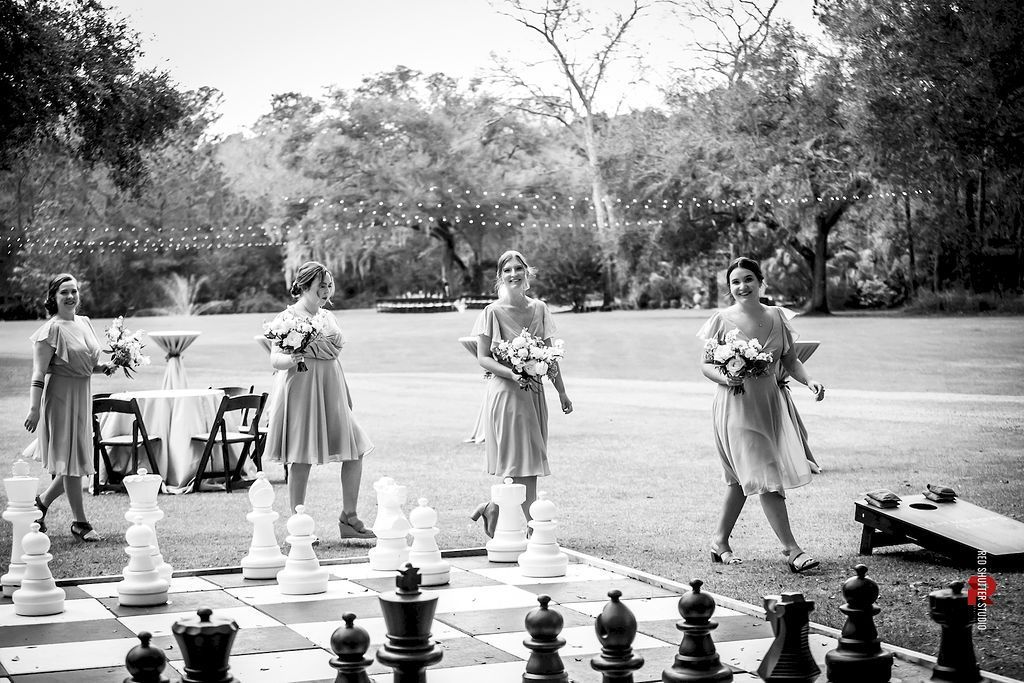 People on giant chess pieces playing outdoor chess in a park, with oversized black-and-white pieces in the foreground