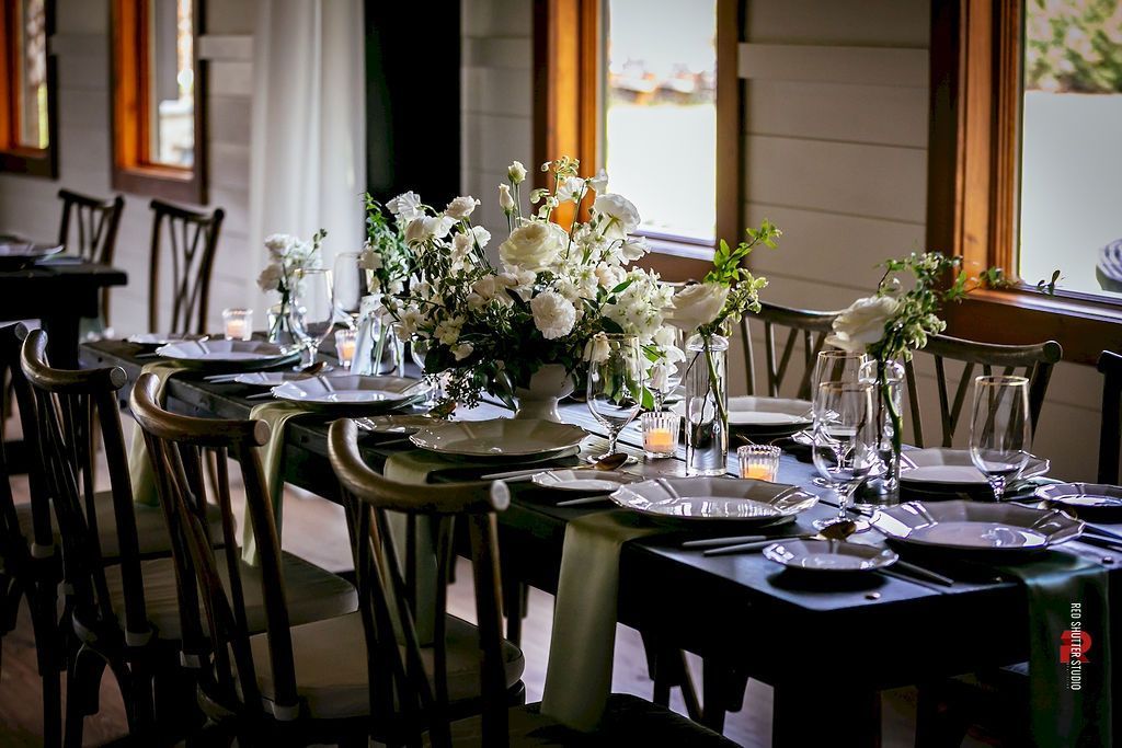 Elegant dining room with set tables, black chairs, and white floral centerpieces