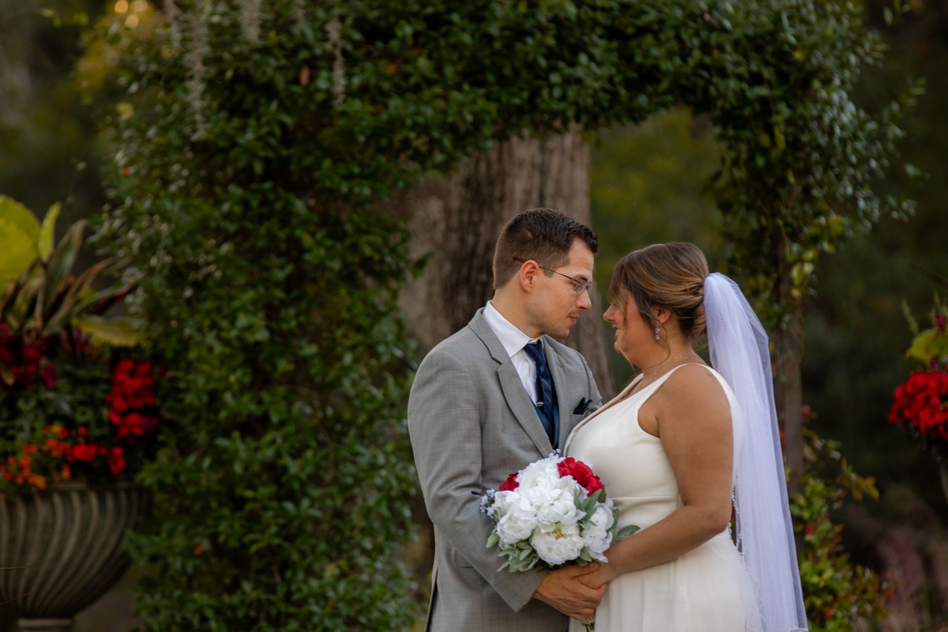 Bride and groom sharing a kiss in a garden, bride holding a white bouquet