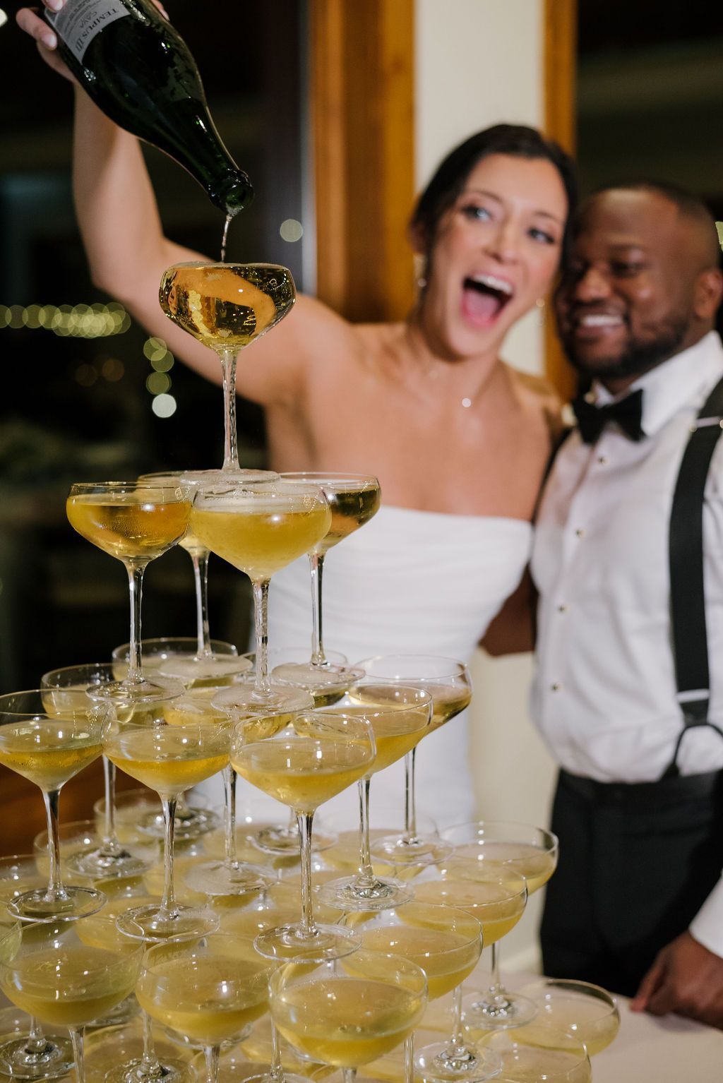 Woman and man pouring champagne into a pyramid of glasses at a celebration